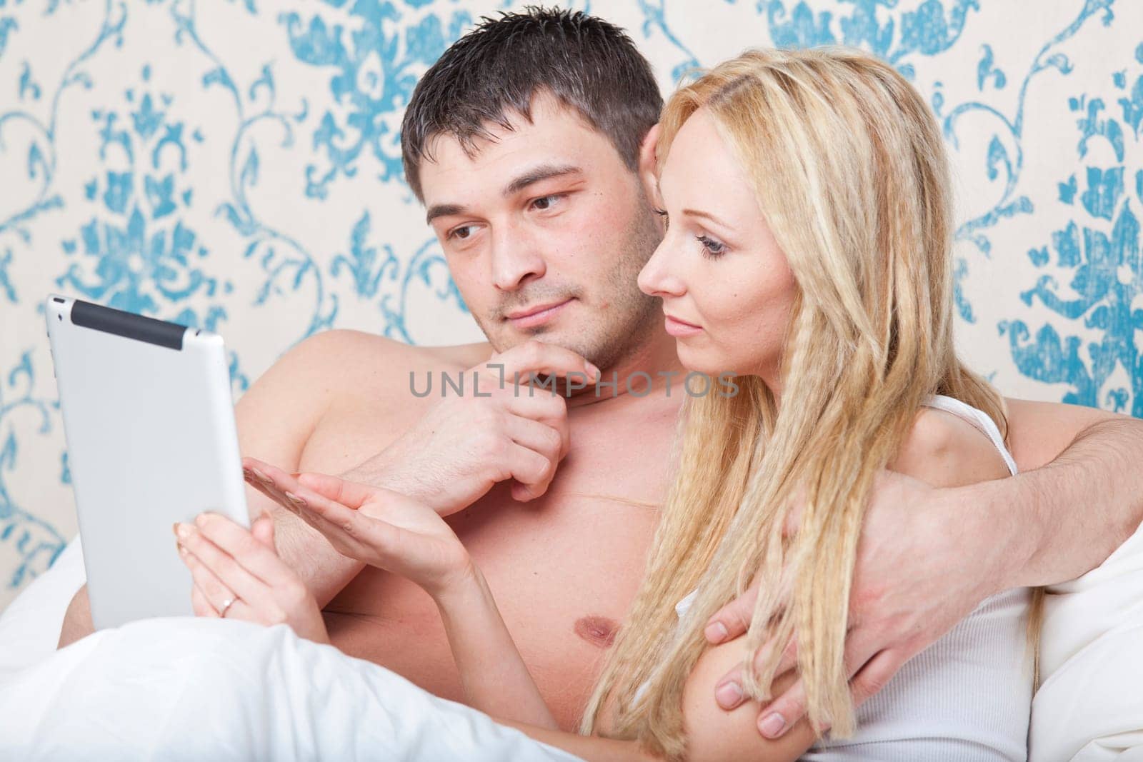 Couple in bed with tablet computer watching a movie