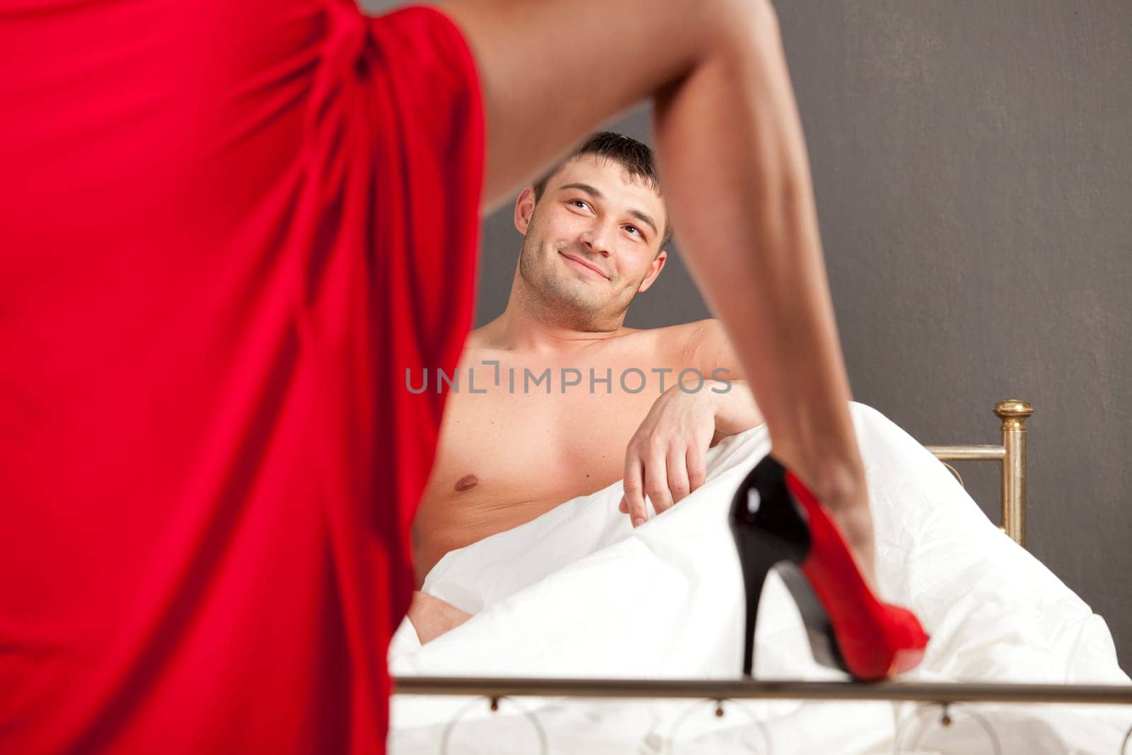 woman in stiletto seducing man in bed