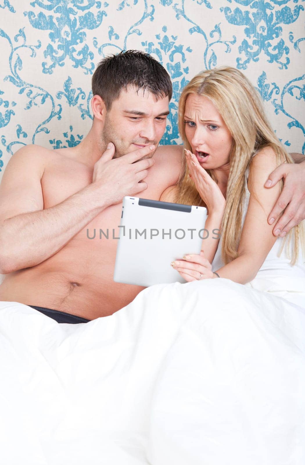 Couple in bed with tablet computer watching a movie