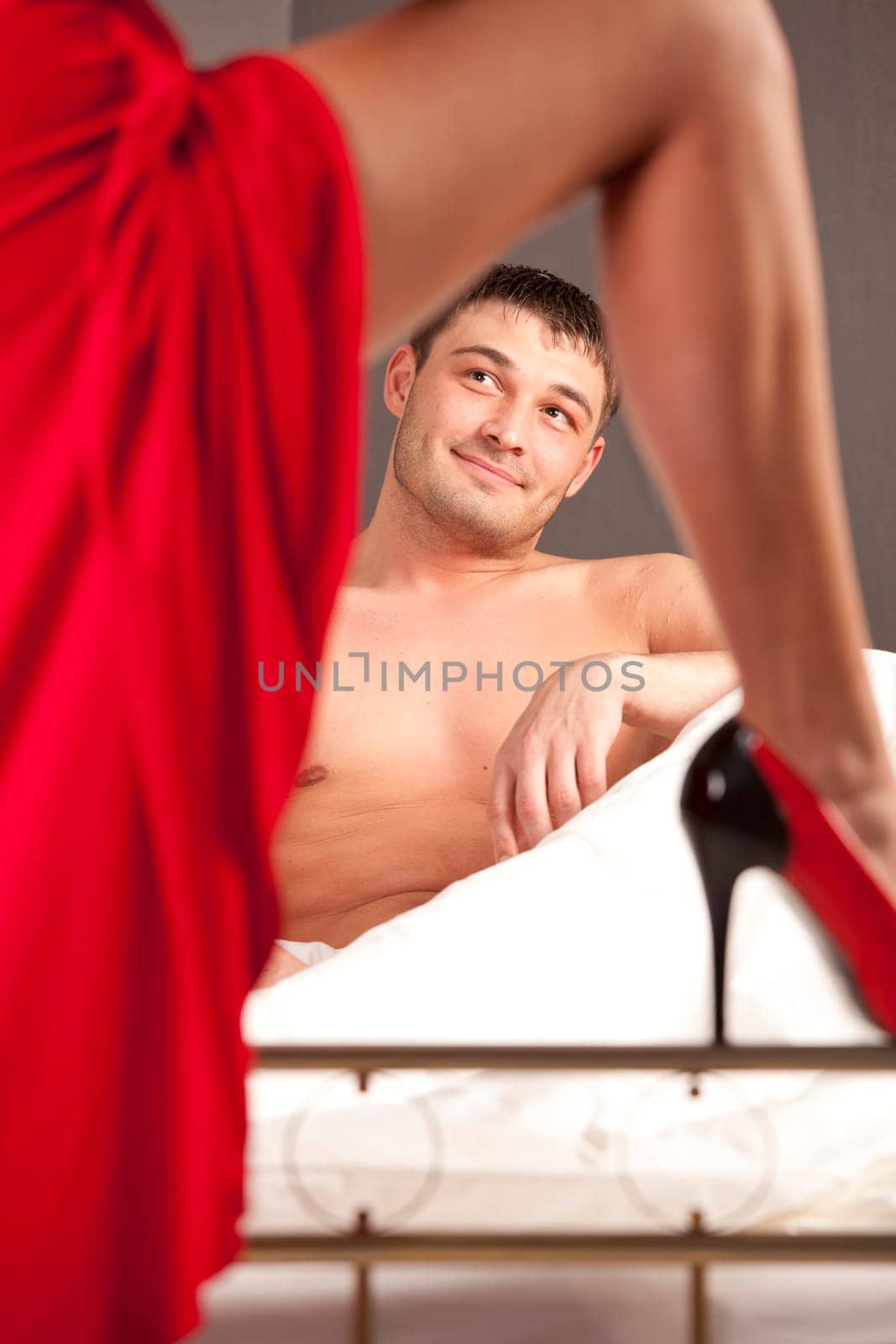 woman in stiletto seducing man in bed
