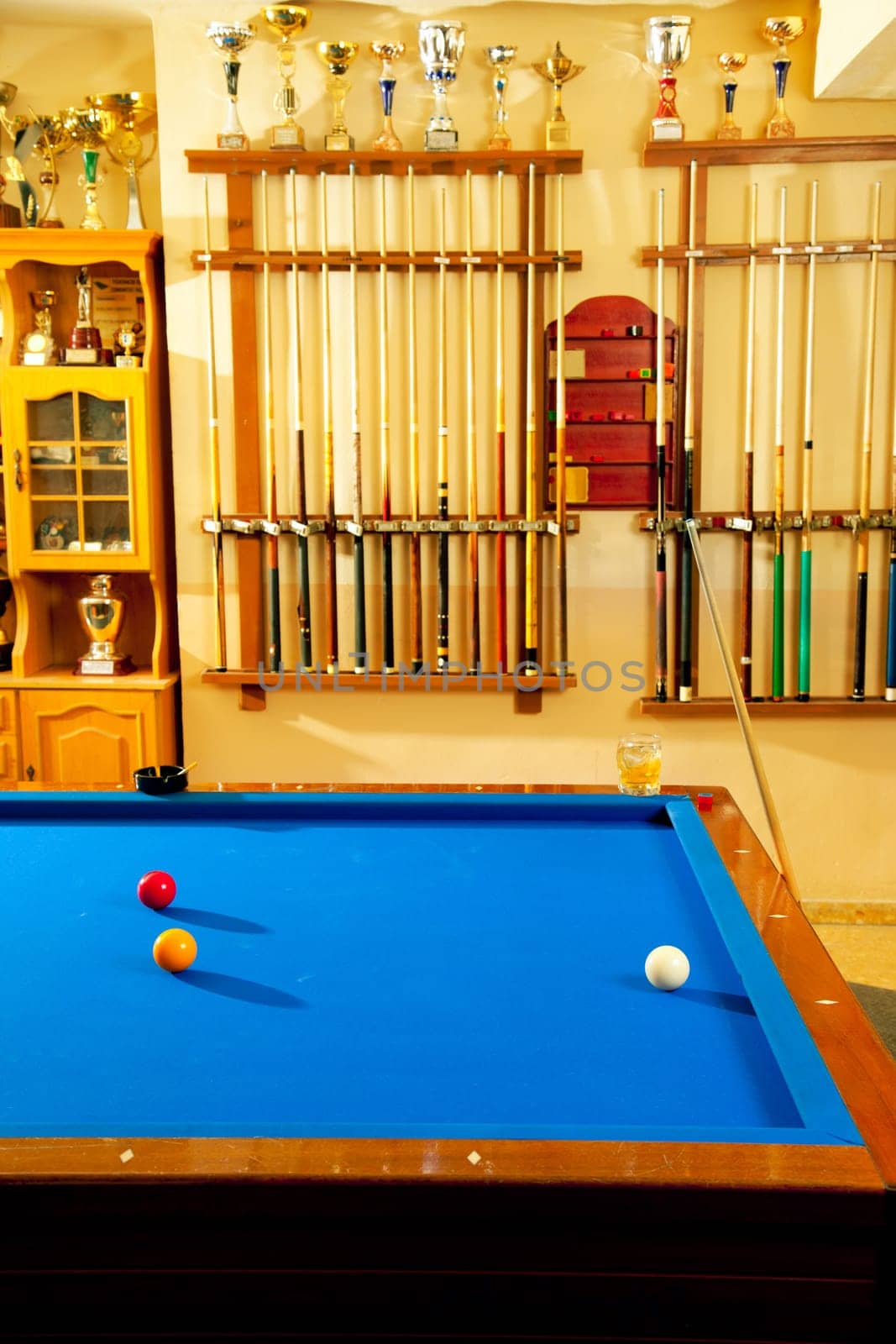 Billiard club with blue pool table cue in a row and winner trophy