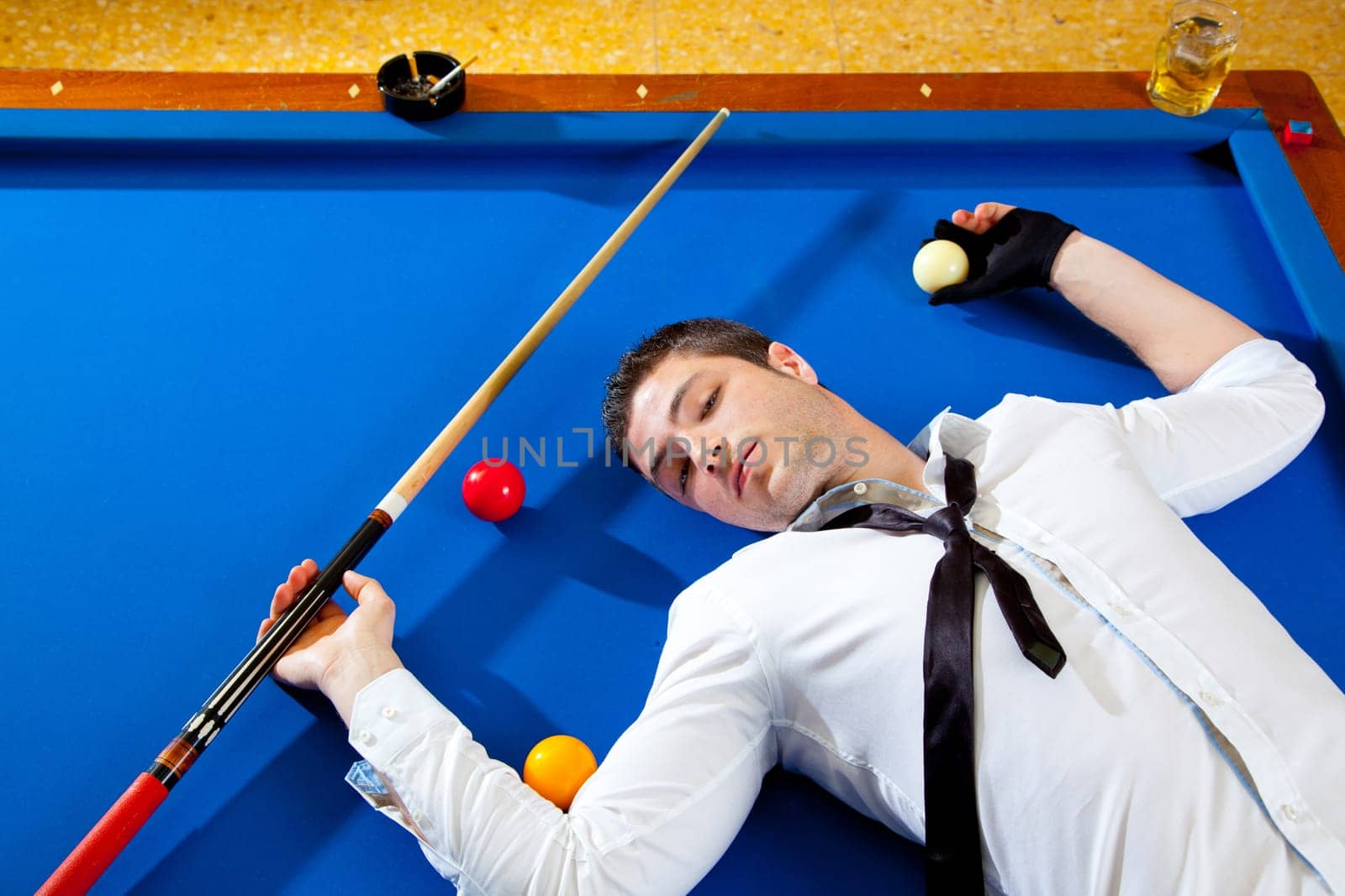 billiard young man player lying on pool blue table with balls