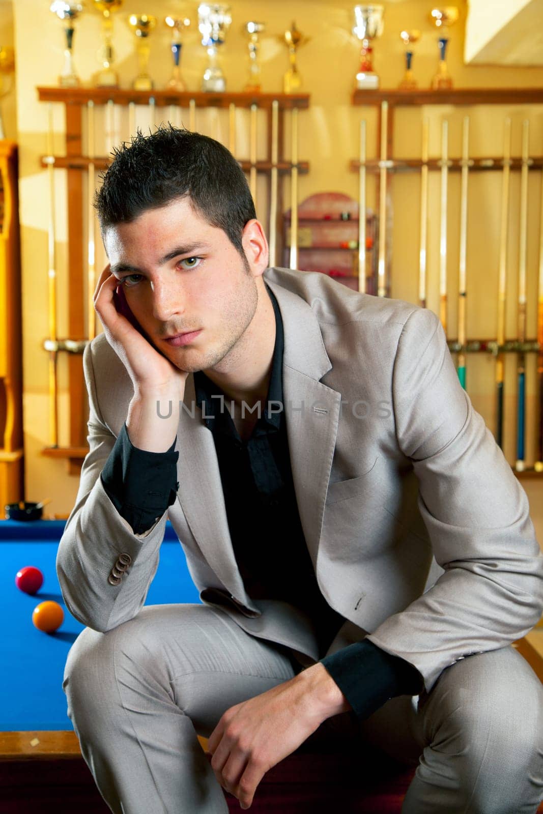 handsome man with suit sitting posing in billiard pool in club
