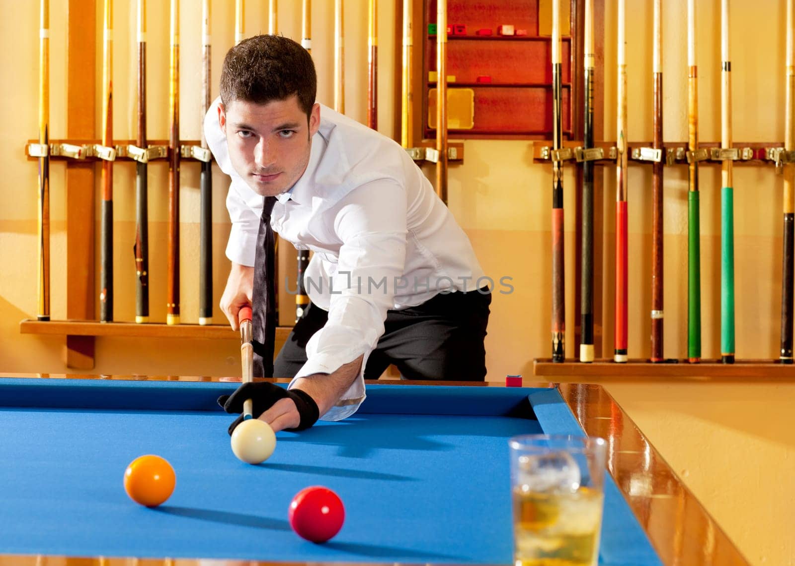 Billiard winner handsome man playing with cue and balls at club