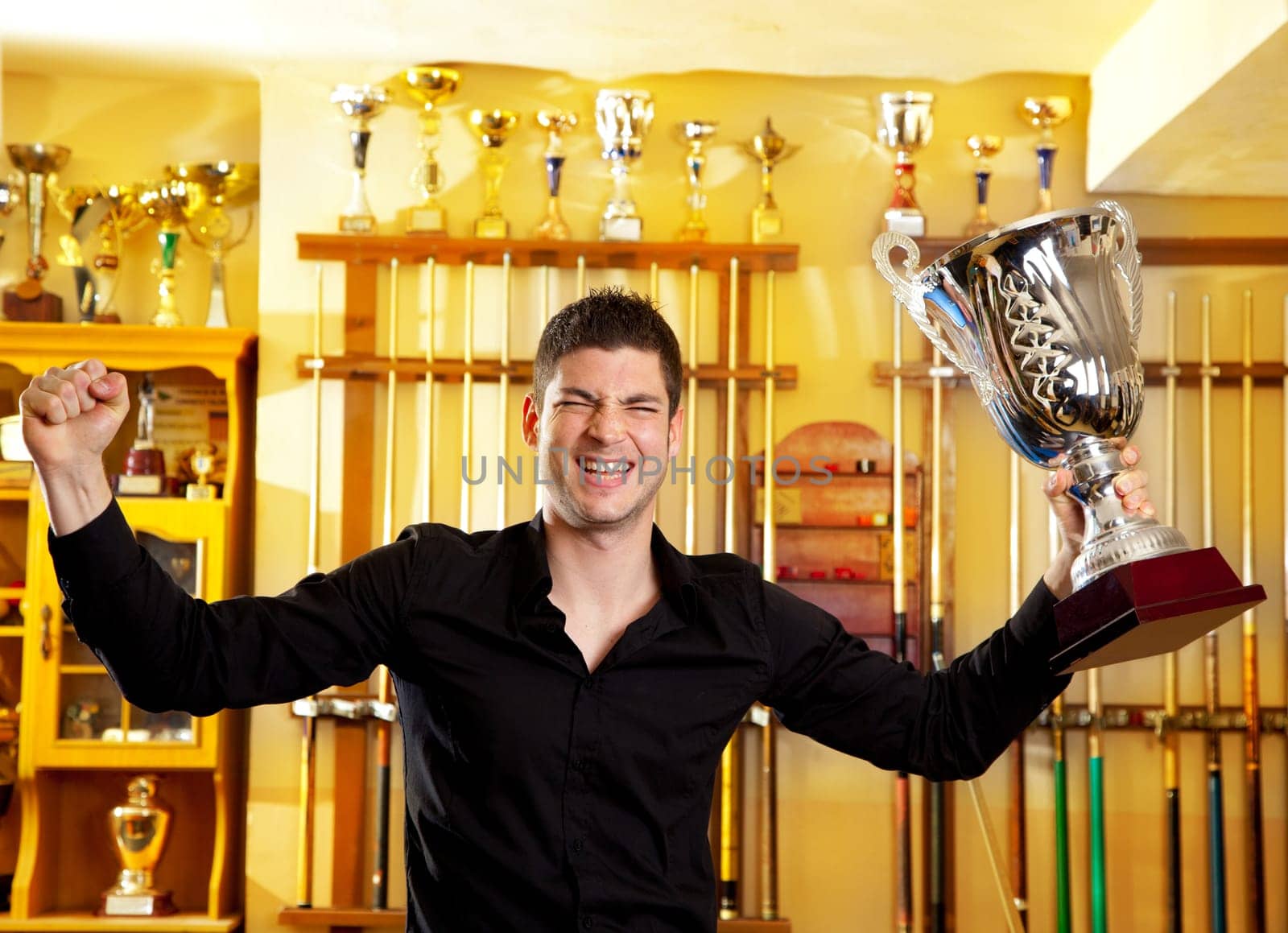 Happy proud winner man with big trophy silver cup in billiard club