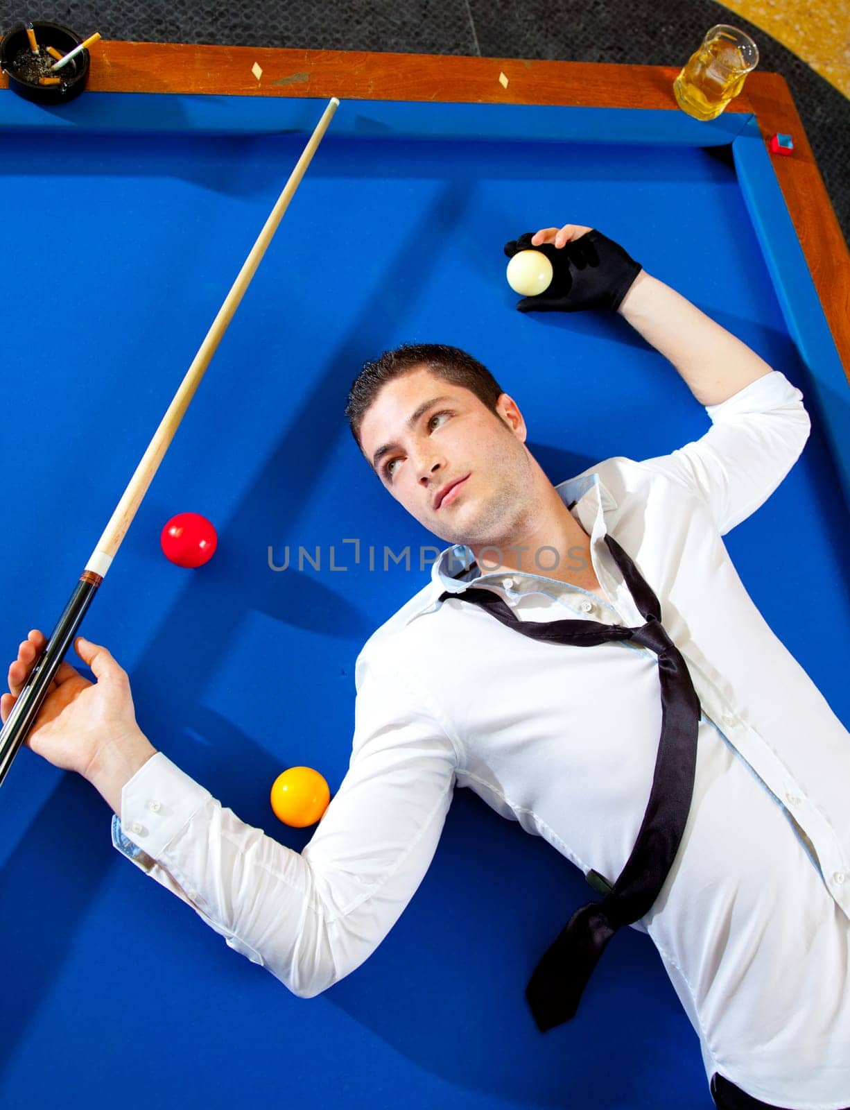 billiard young man player lying on pool blue table with balls