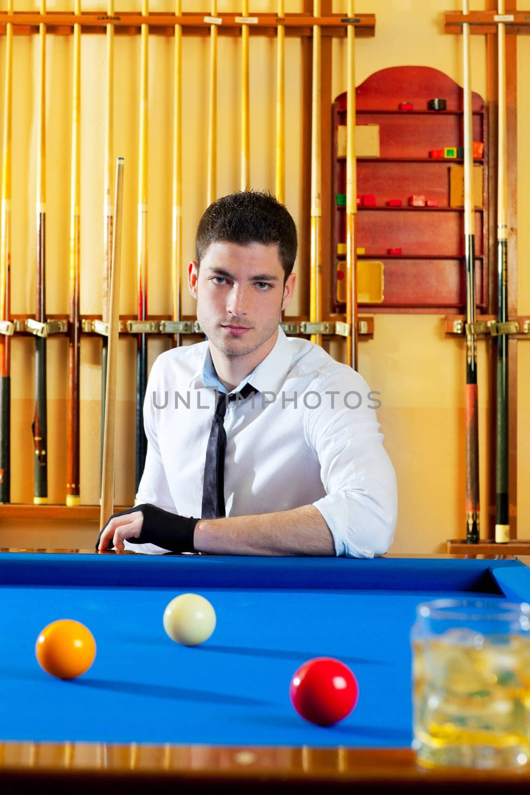 Billiard expertise man posing on blue with alcohol on the rocks glass