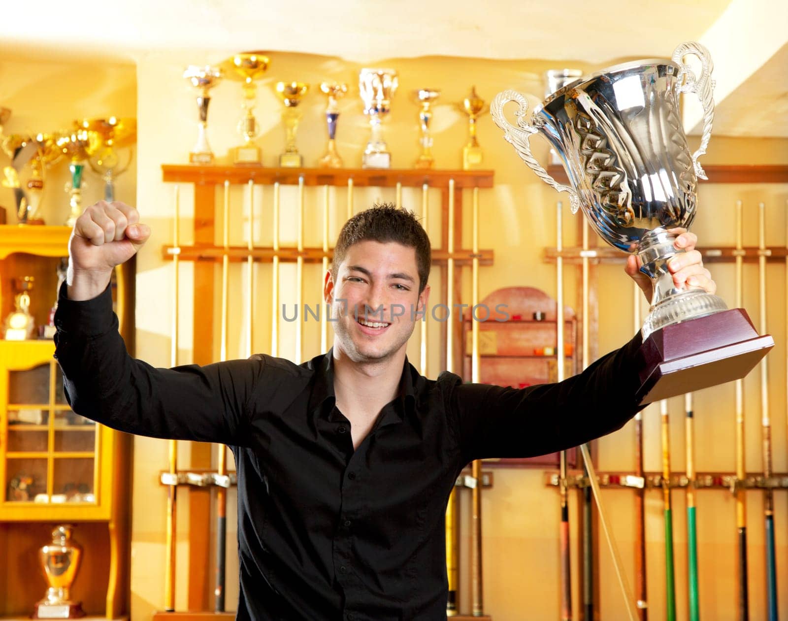 Happy proud winner man with big trophy silver cup in billiard club