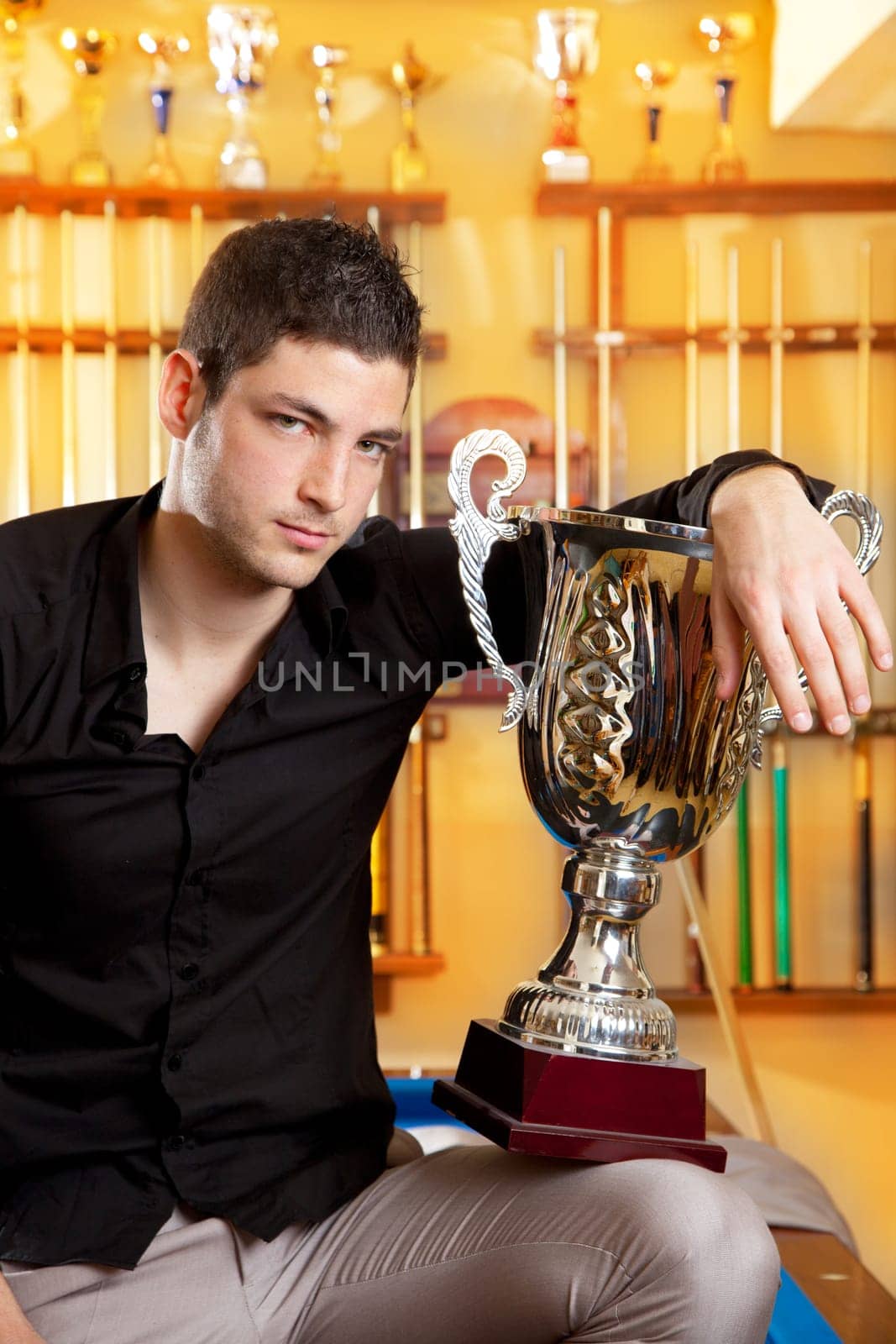 Happy proud winner man with big trophy silver cup in billiard club