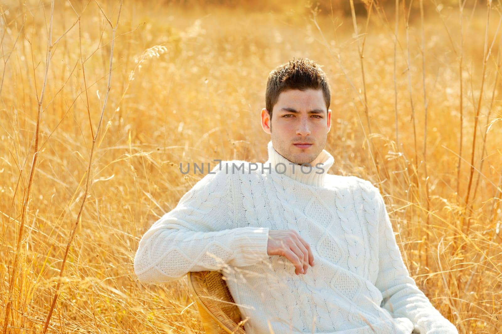 Autumn winter man portrait in outdoor dried grass field with turtleneck sweater