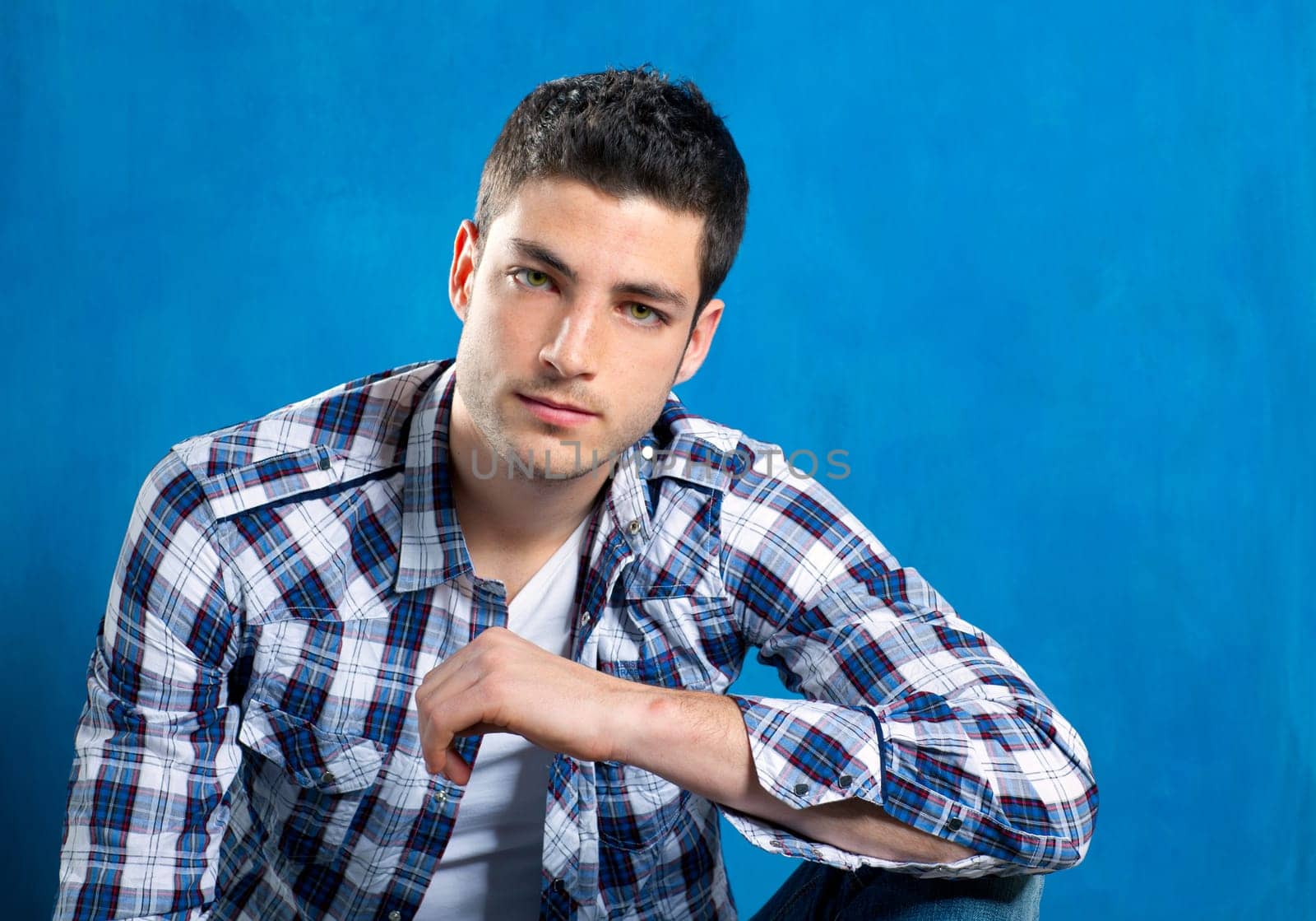handsome young man with plaid shirt on blue background