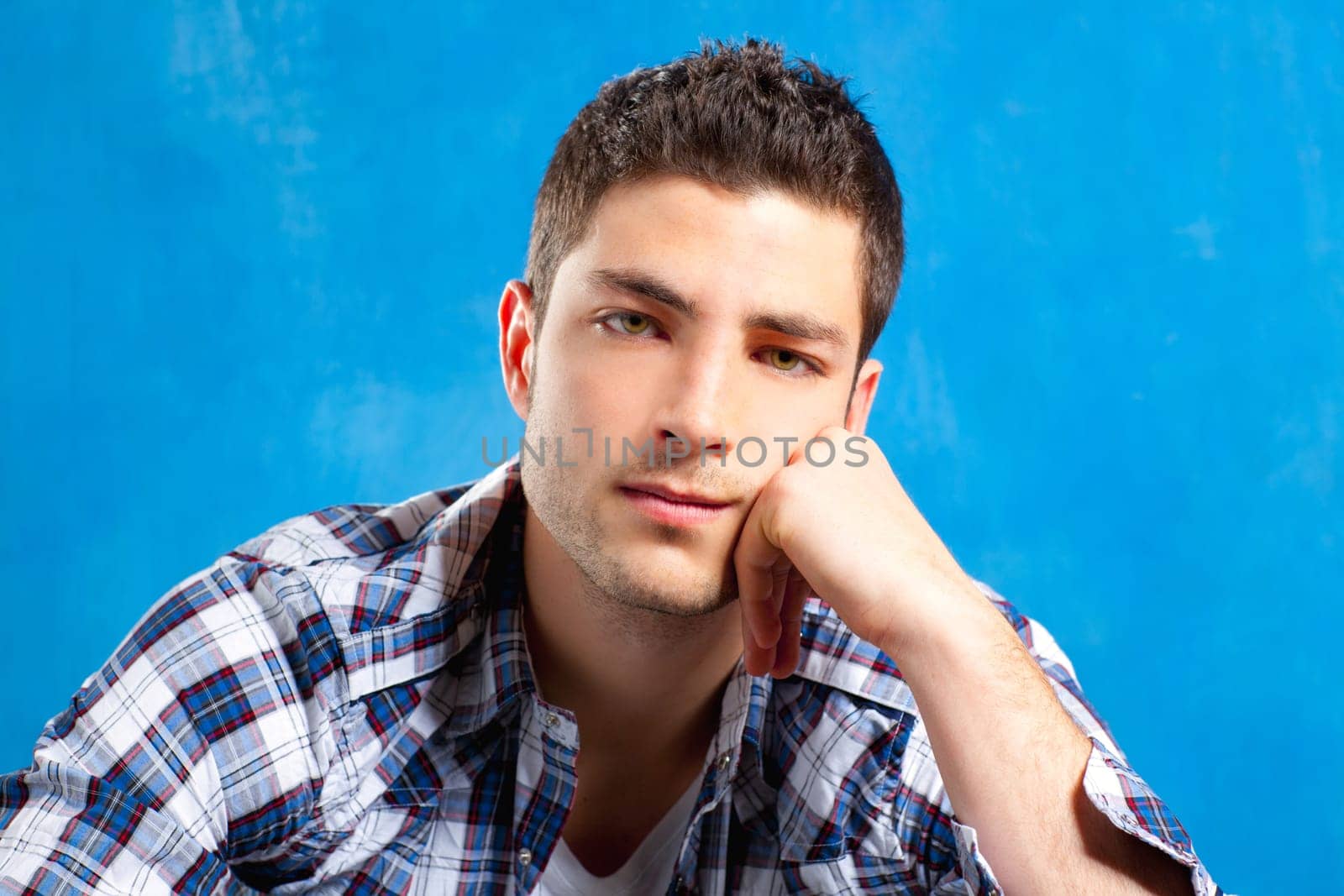 handsome young man with plaid shirt on blue background