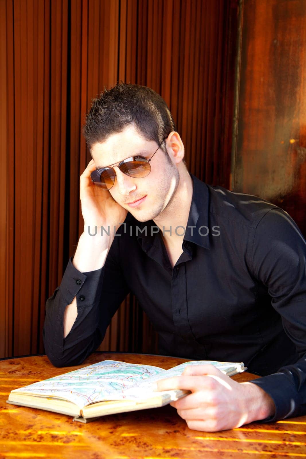 Latin tourist man reading a map book with sunglasses