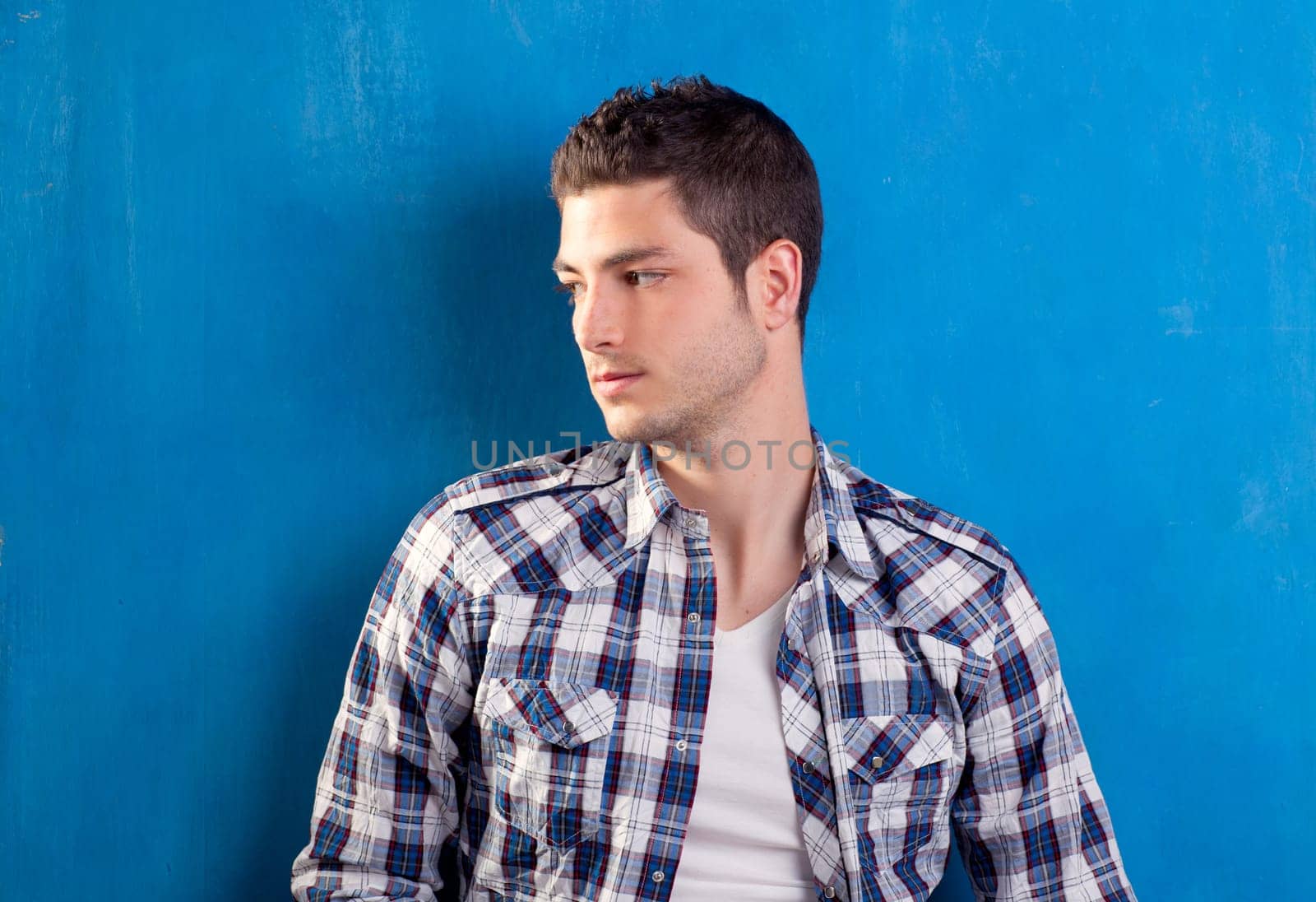 handsome young man with plaid shirt on blue background