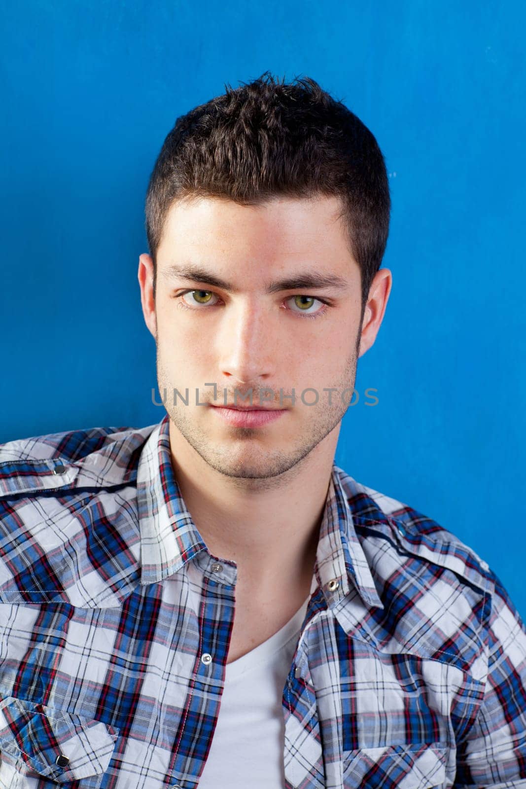 handsome young man with plaid shirt on blue background