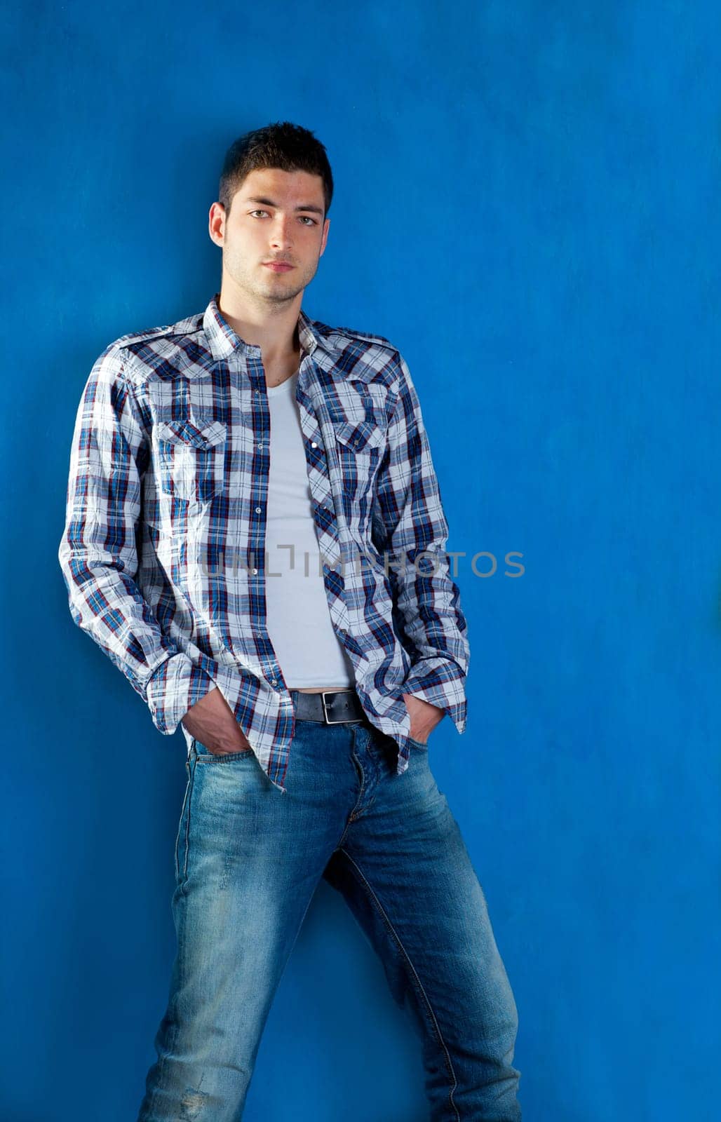 handsome young man with plaid shirt denim jeans in blue background