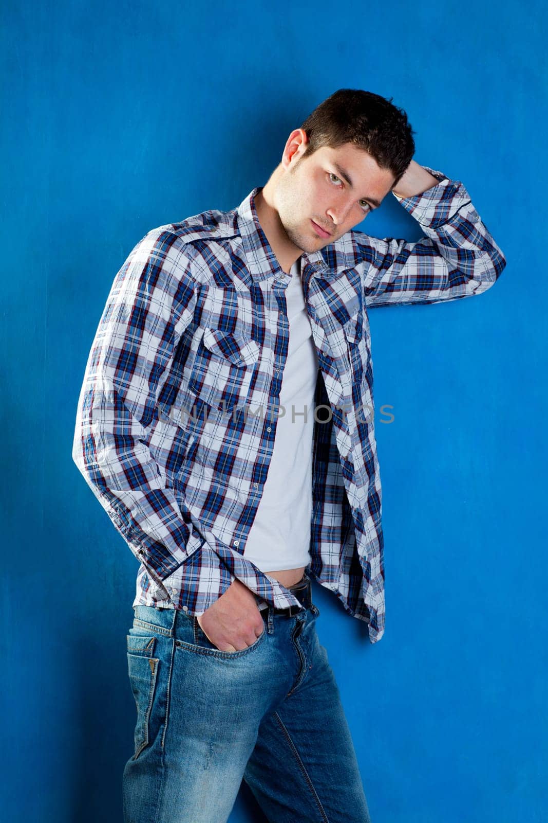 handsome young man with plaid shirt denim jeans in blue background