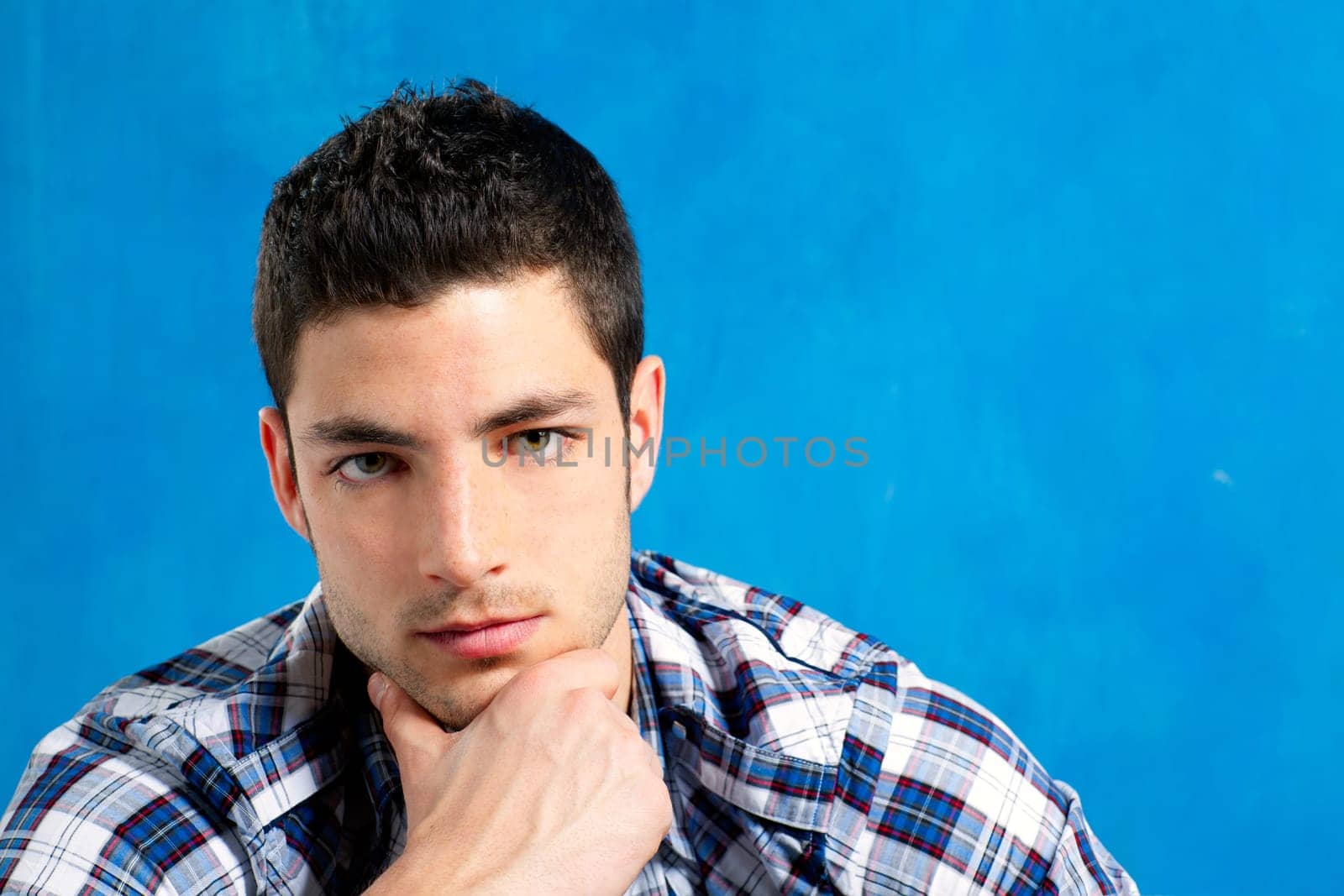 handsome young man with plaid shirt on blue background