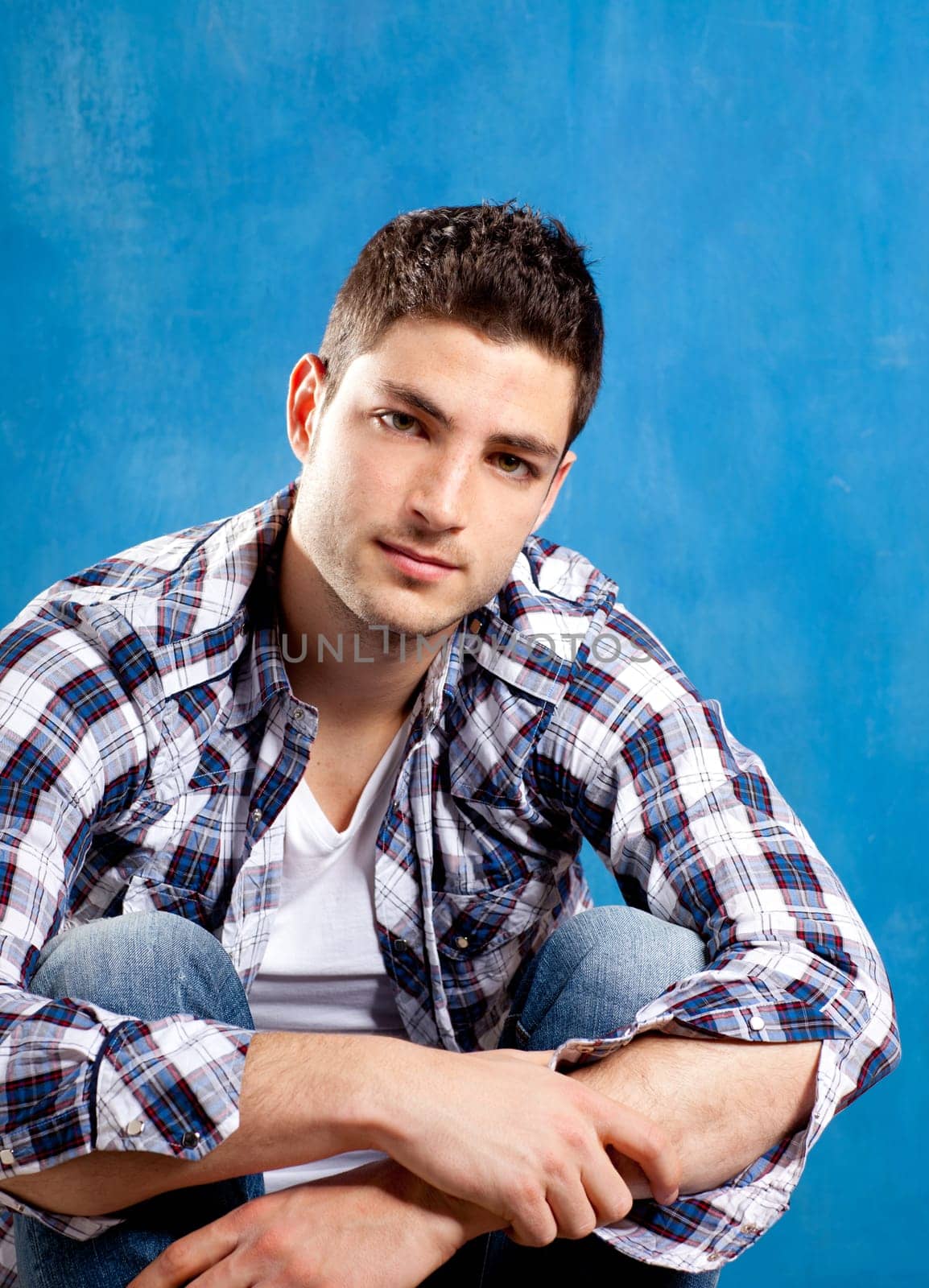 handsome young man with plaid shirt on blue background