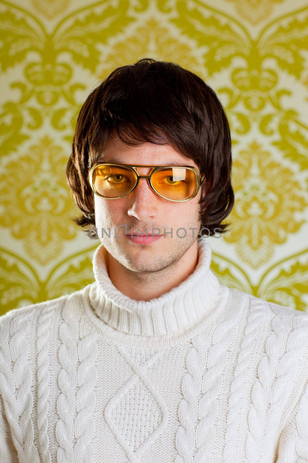 retro hip young man with vintage glasses and winter  turtleneck sweater on wallpaper