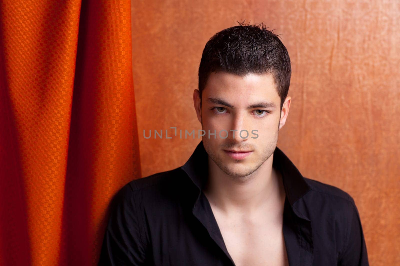 Latin spanish man portrait open black shirt with curtain and orange vintage background