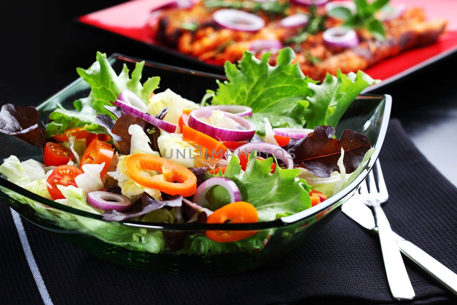 Mixed vegetable salad grilled meat in background