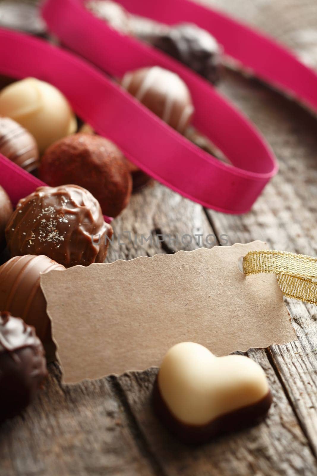 Heart-shaped Truffle with a message card with a pink ribbon on wooden background