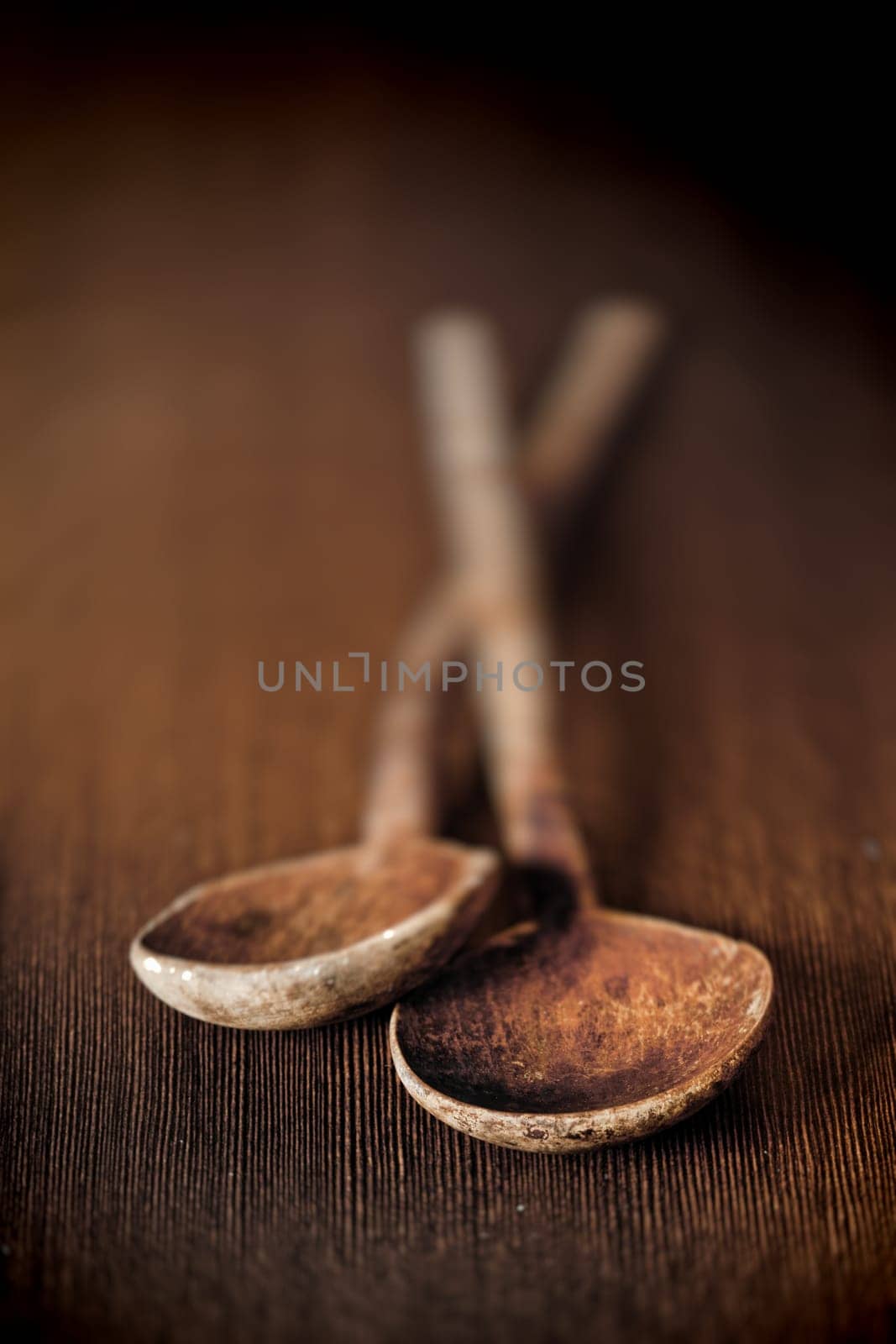 Background of two old wooden kitchen mixing spoons on a table top with bowls towards the camera and shallow depth of field