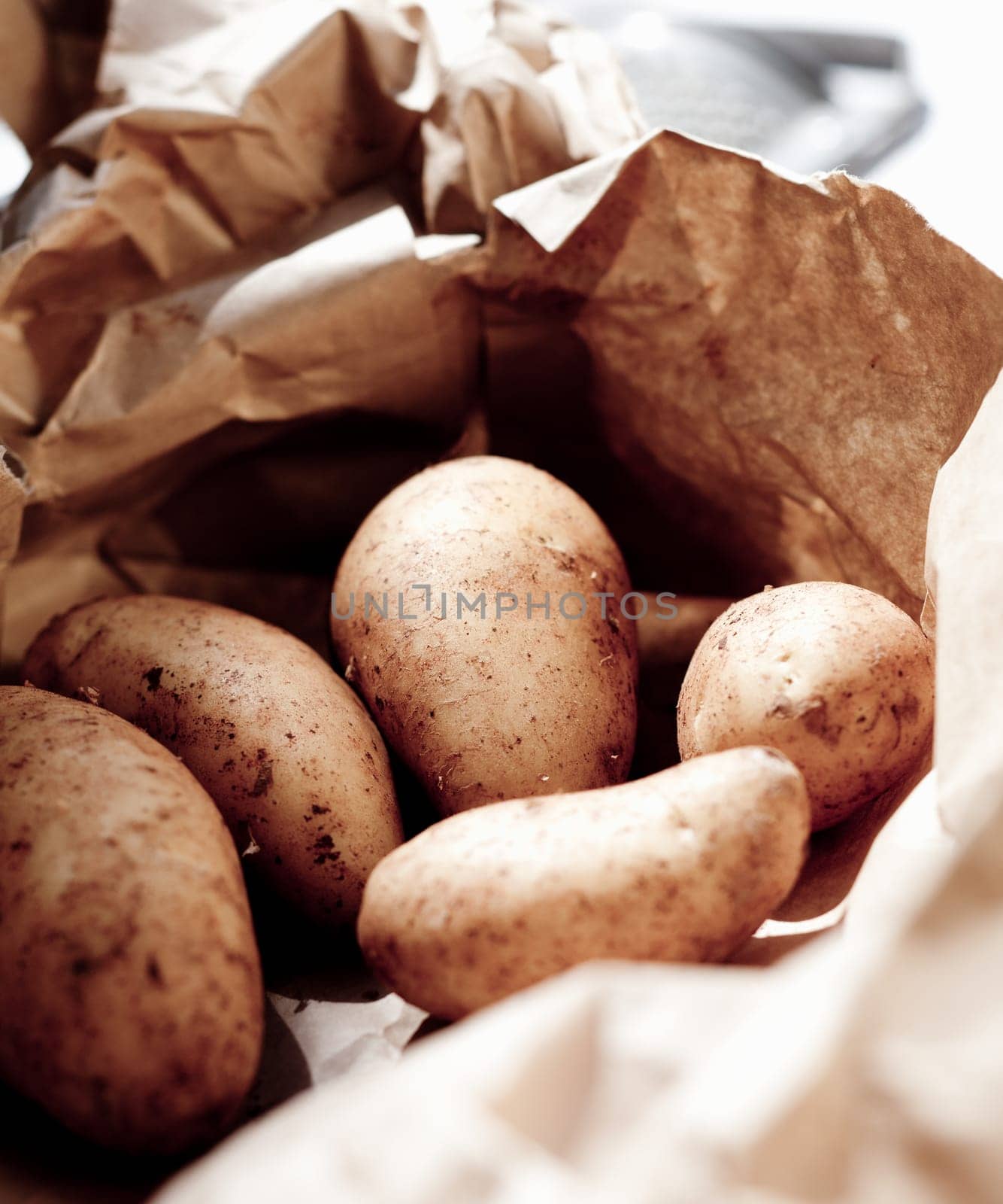 Closeup of fresh unwashed potatoes for sale at market in a recyclable brown paper bag