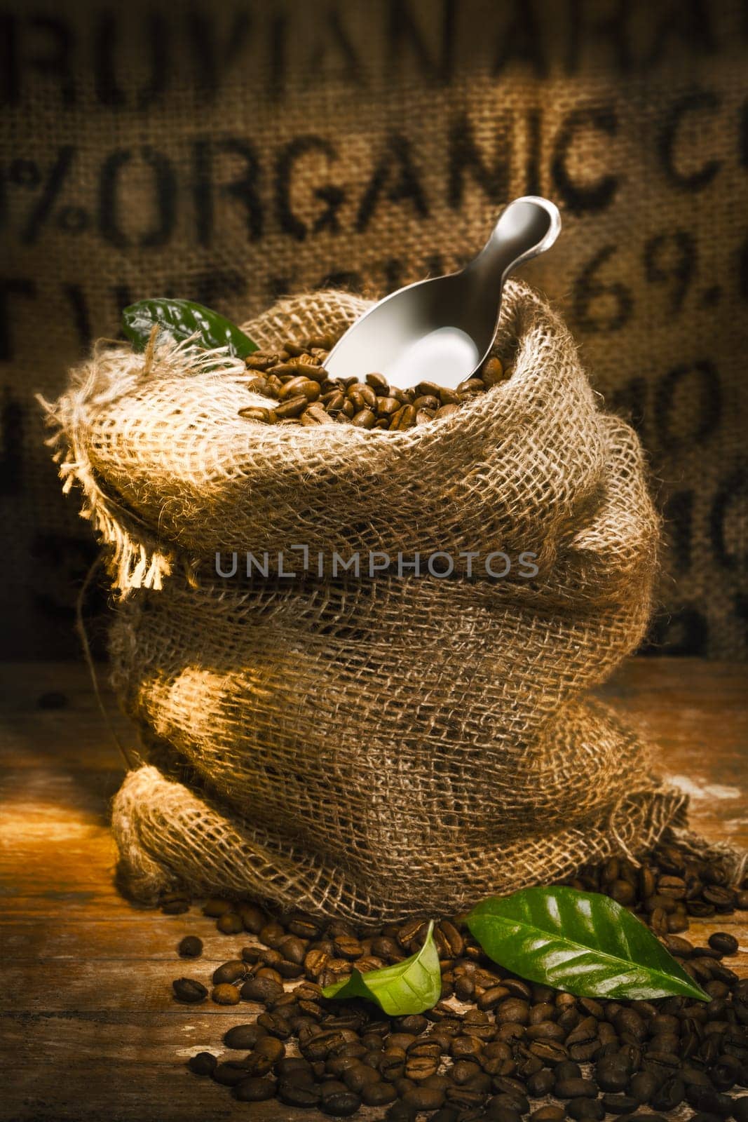 Small hessian sack filled with fresh roasted coffee beans topped by a small shovel with the word Organic highlighted on hessian in the background, conceptual of organically grown coffee