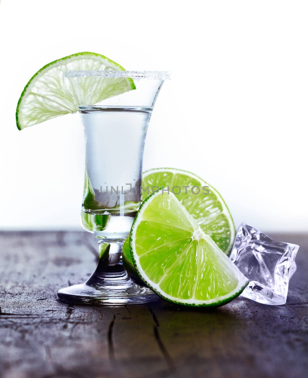 Tall glass with cool drink and lime slice with ice and lime on an outdoor table
