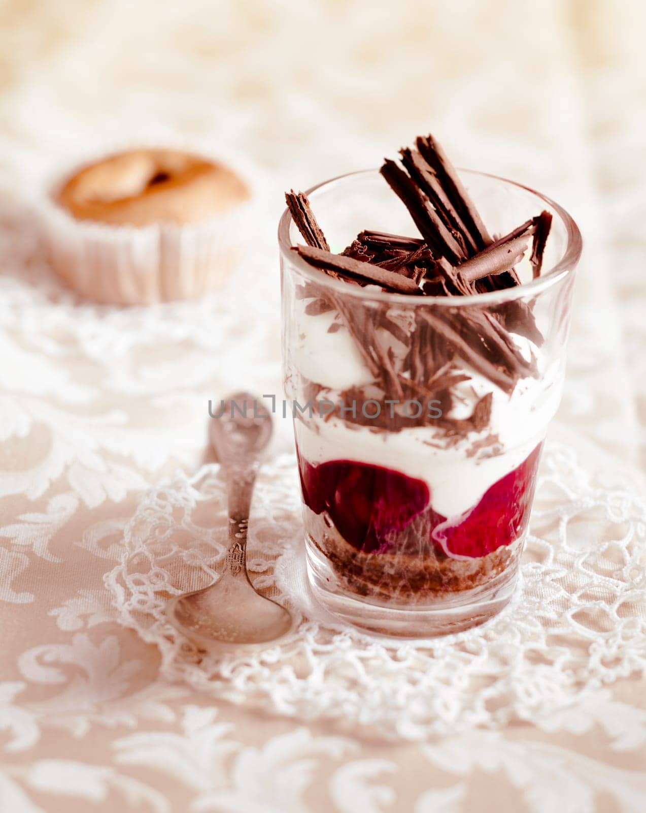 Gourmet fruit and cream parfait topped with chocolate shavings and served in a clear glass on a decorative doily