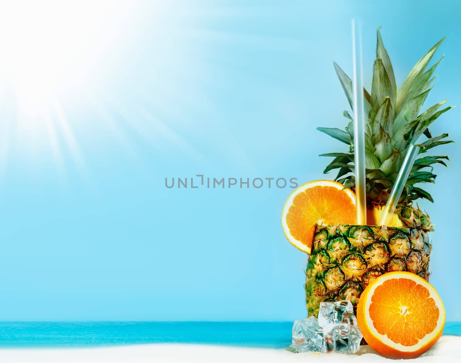 Fresh pineapple with oranges, tubules and ice on sunny beach with copy space