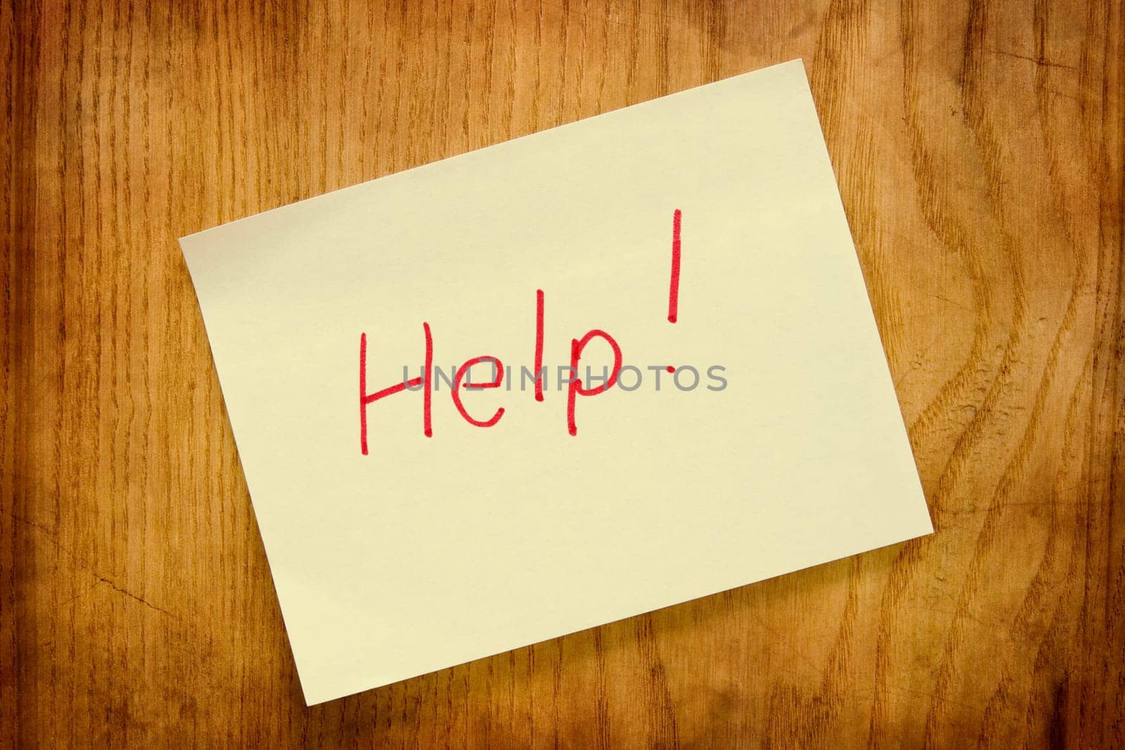 Yellow small sticky note on a wooden board. Help message.