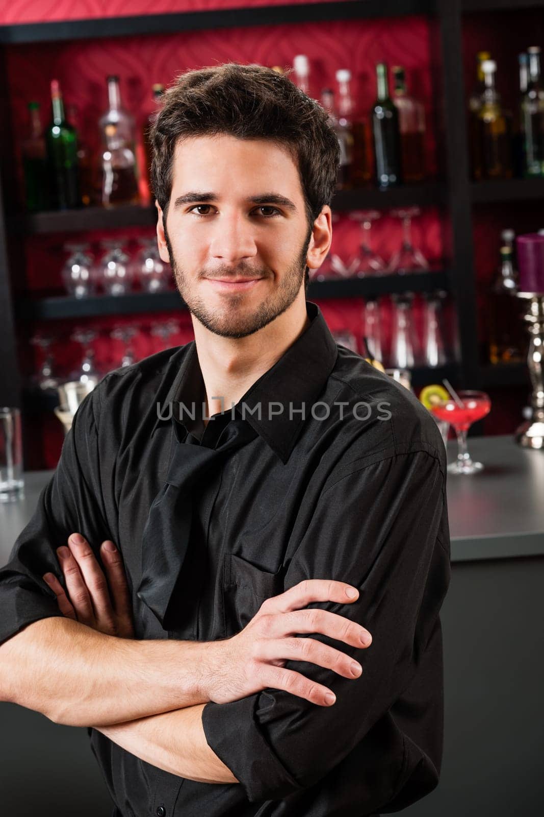 Portrait of handsome barman standing in front of the bar
