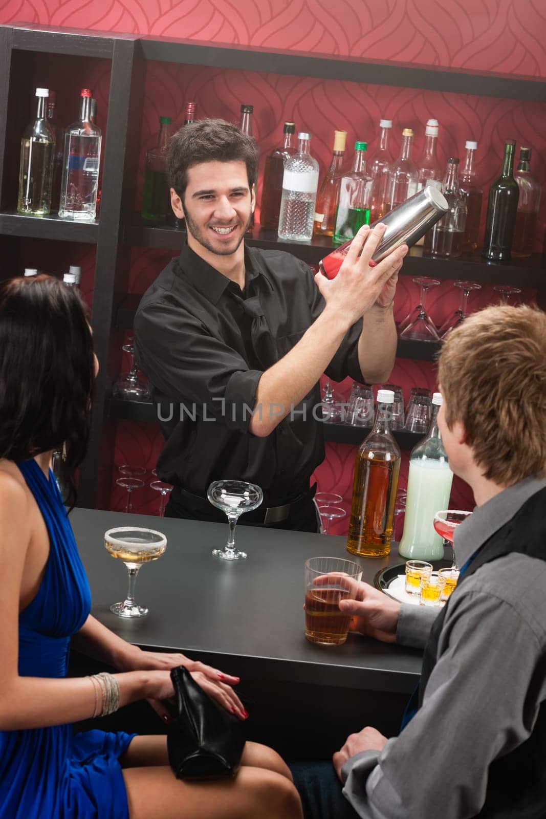 Barman making cocktail for young couple at the bar
