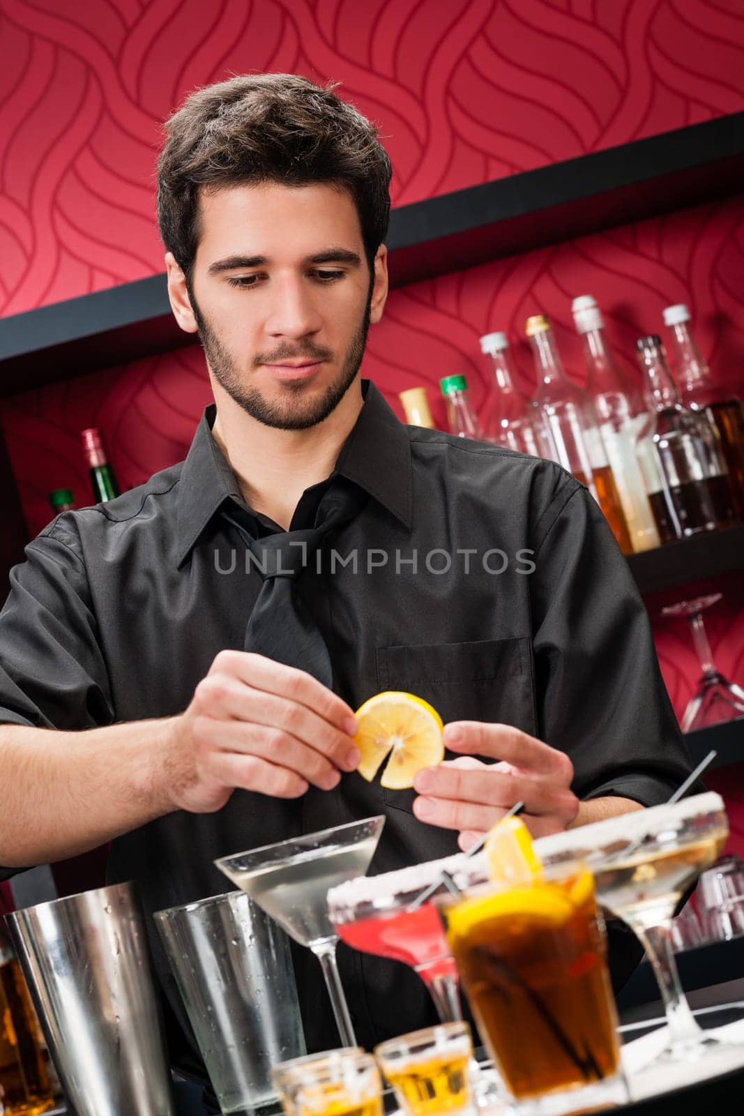 Handsome barman professional at posh bar making cocktail drinks