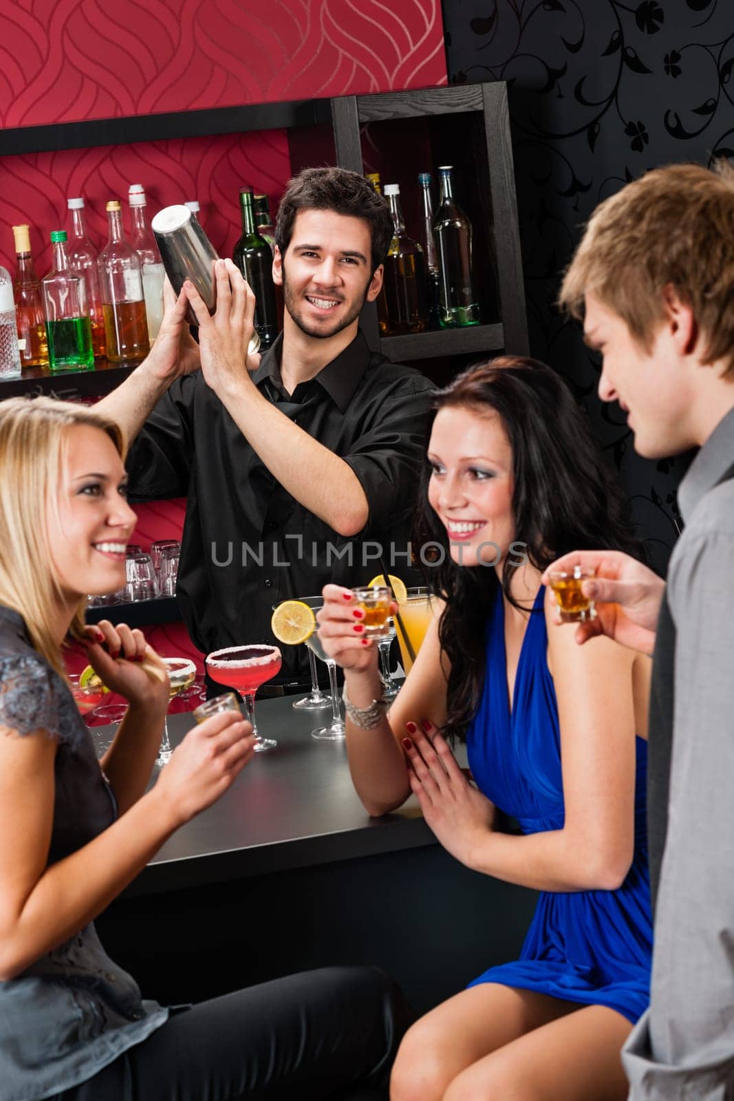 Barman making cocktail for young friends at the bar