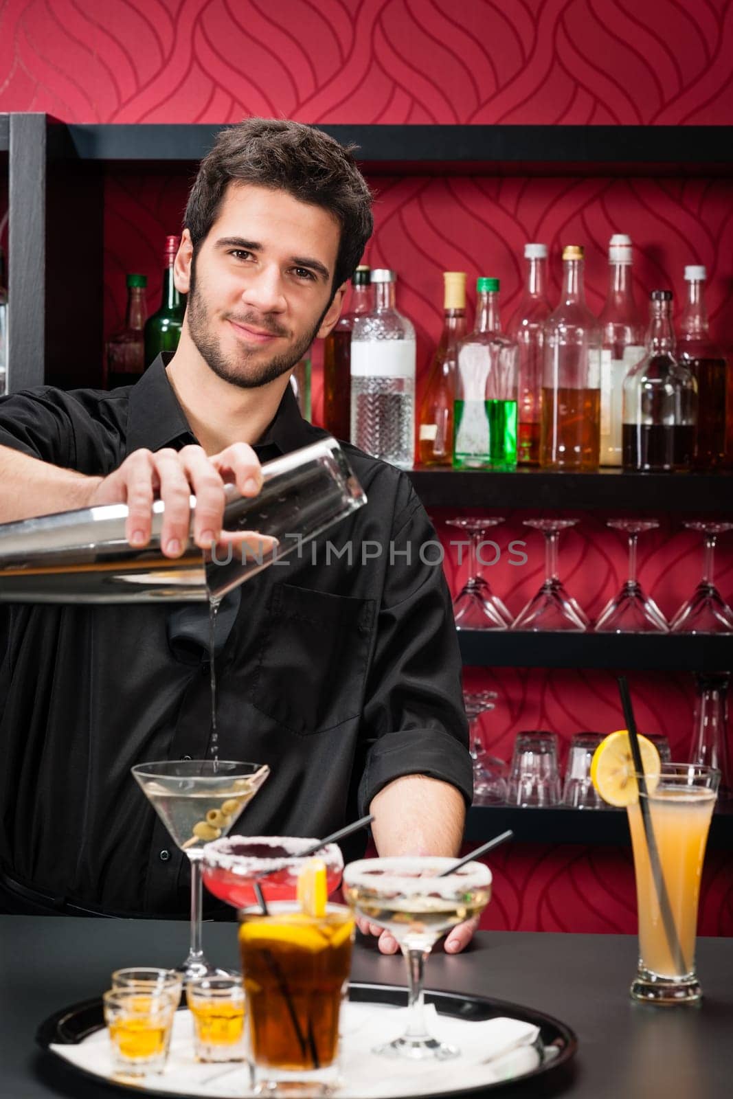 Handsome barman professional at posh bar making cocktail drinks
