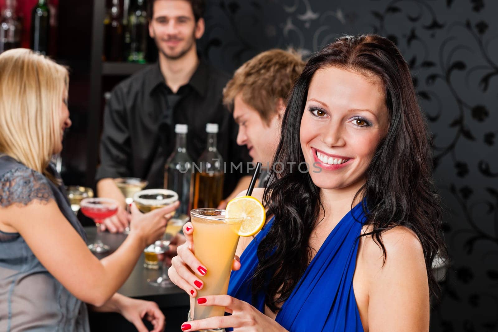 Smiling woman having drink with friends at cocktail bar