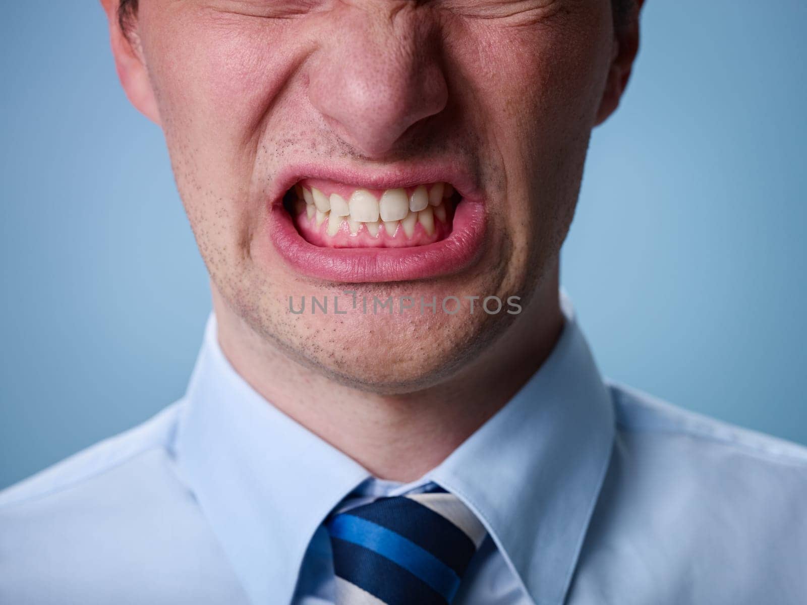 closeup of businessman screaming against blue background. Horizontal shape
