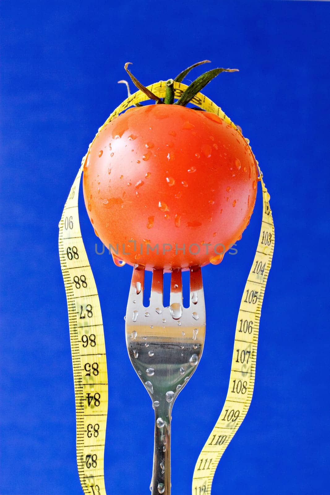 concept for healthy food. fork with tomato and measure tape