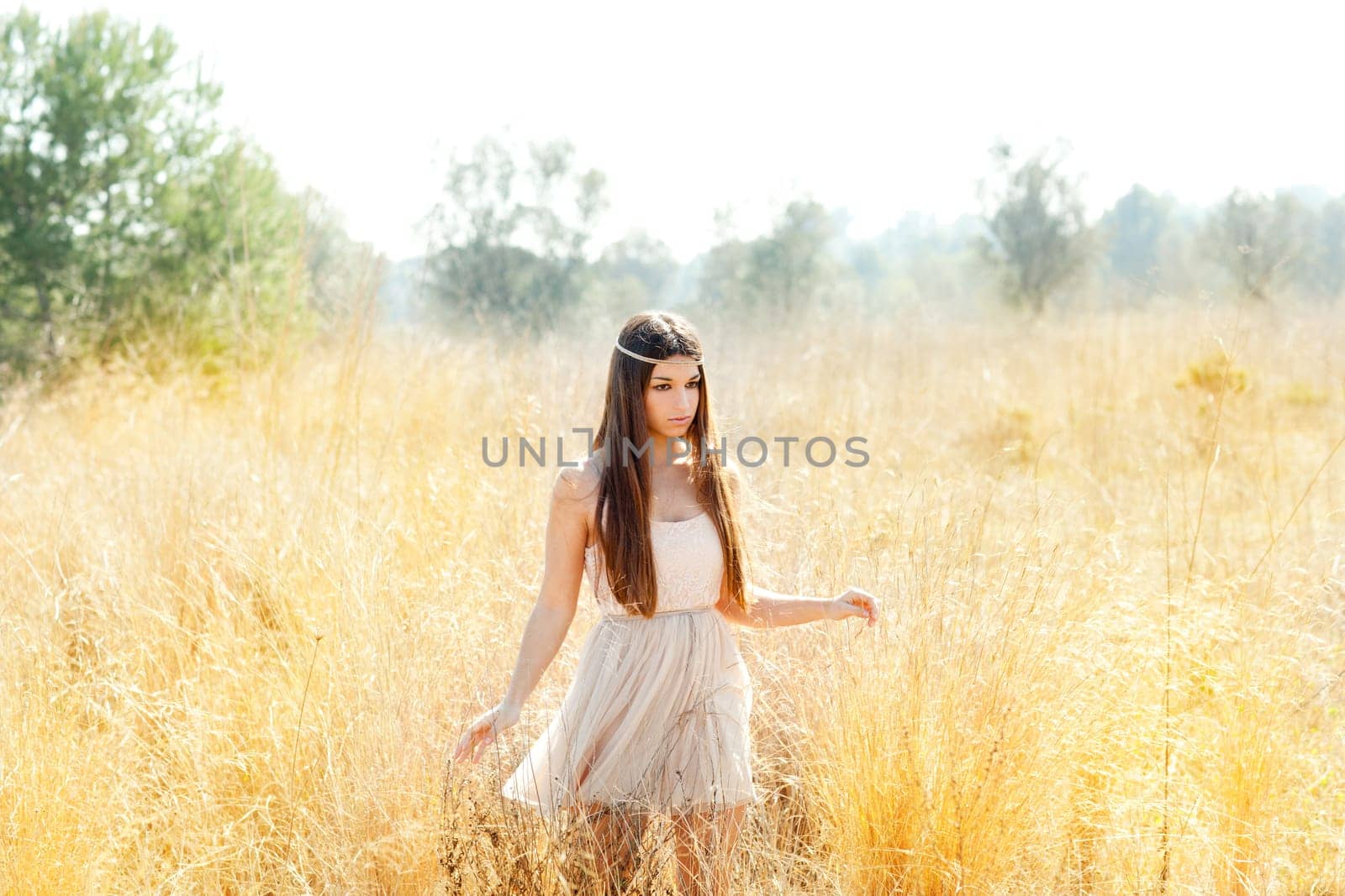 Asian indian woman walking in golden dried grass field