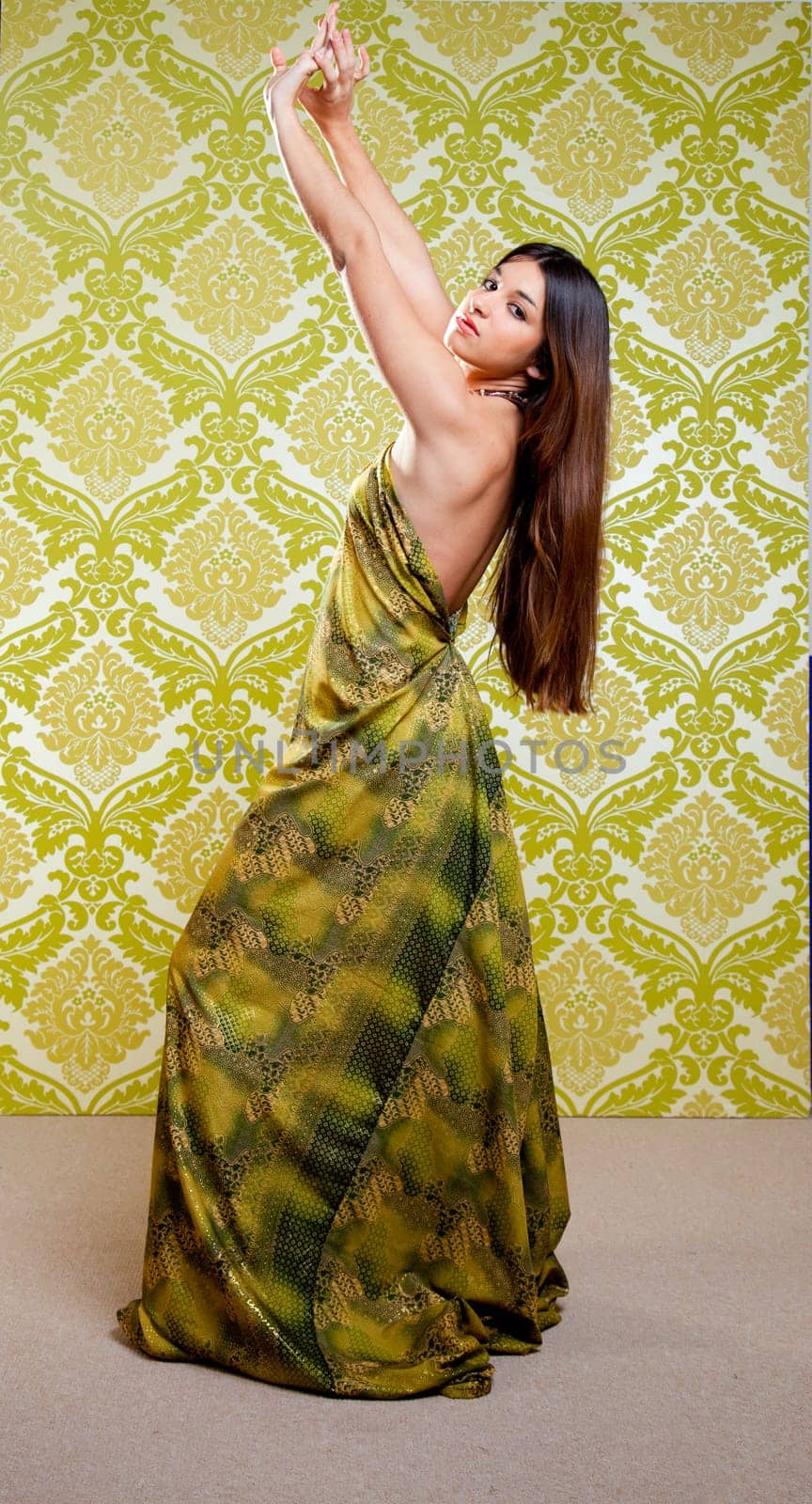 Asian Indian woman dancing full length with ethnic dress on green wallpaper