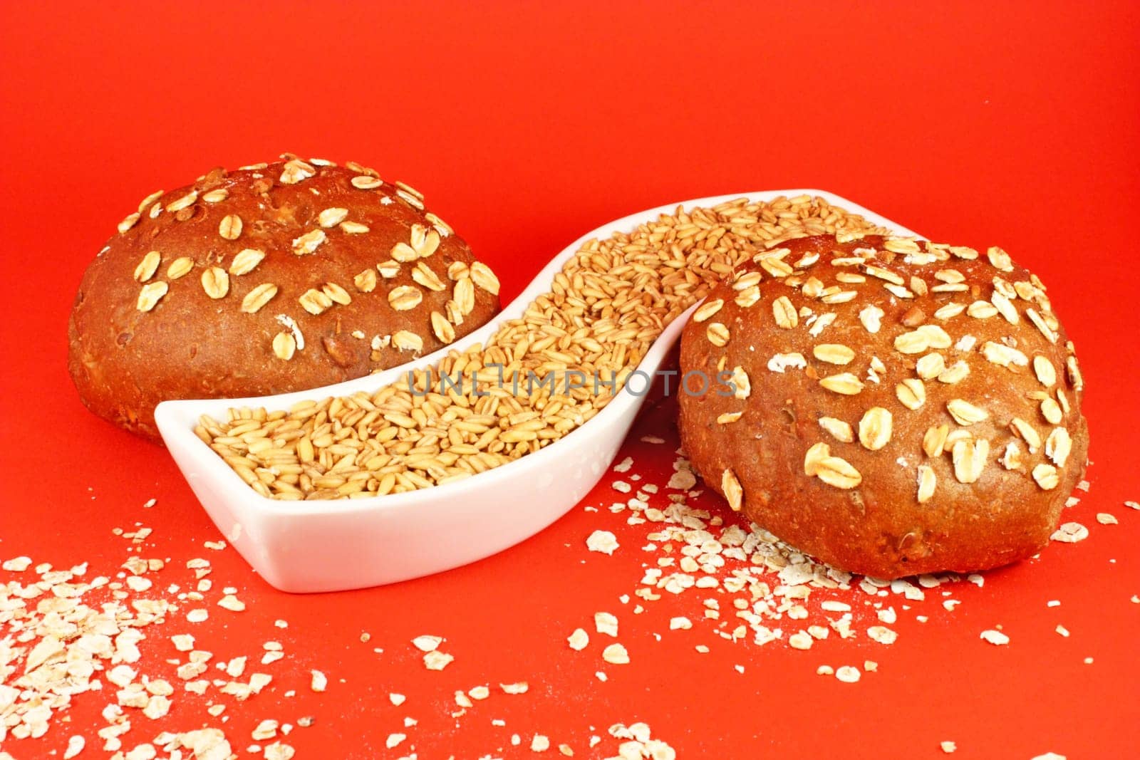 Two pastries with oat seeds on red background