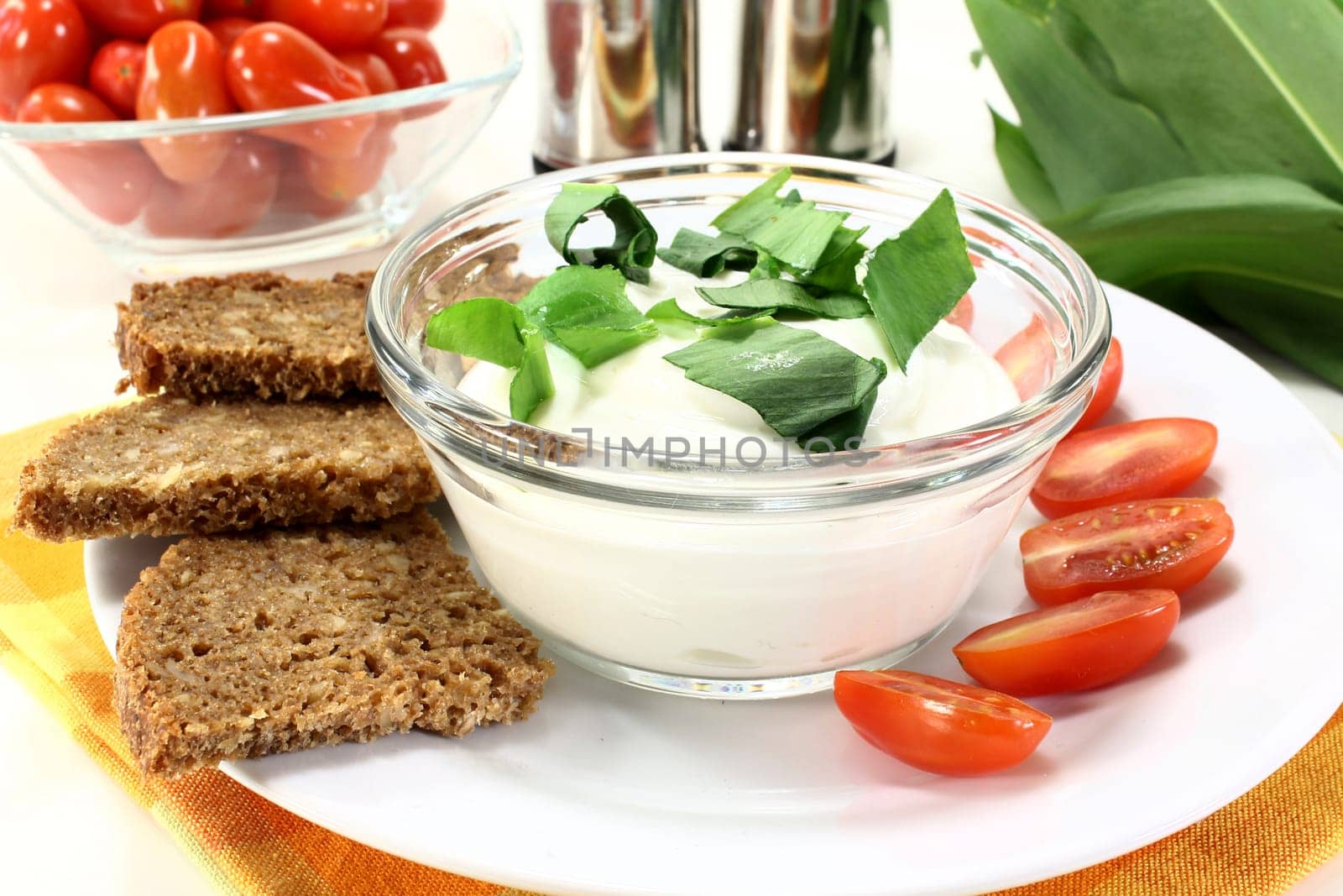 a bowl of wild garlic quark with bread and tomatoes