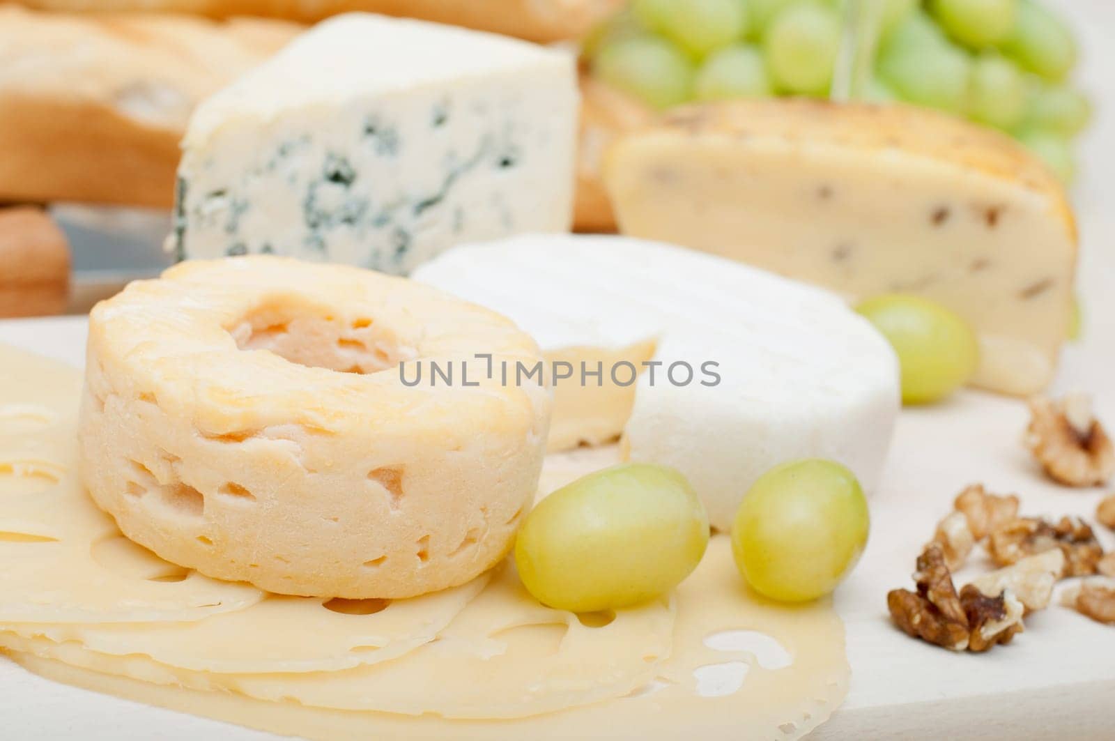 Various Types of Cheese, Grapes and Walnuts on Wooden Chopping Board