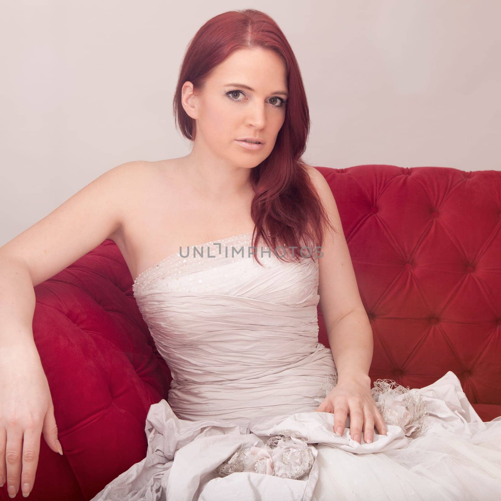 young red haired beautiful bride on red sofa