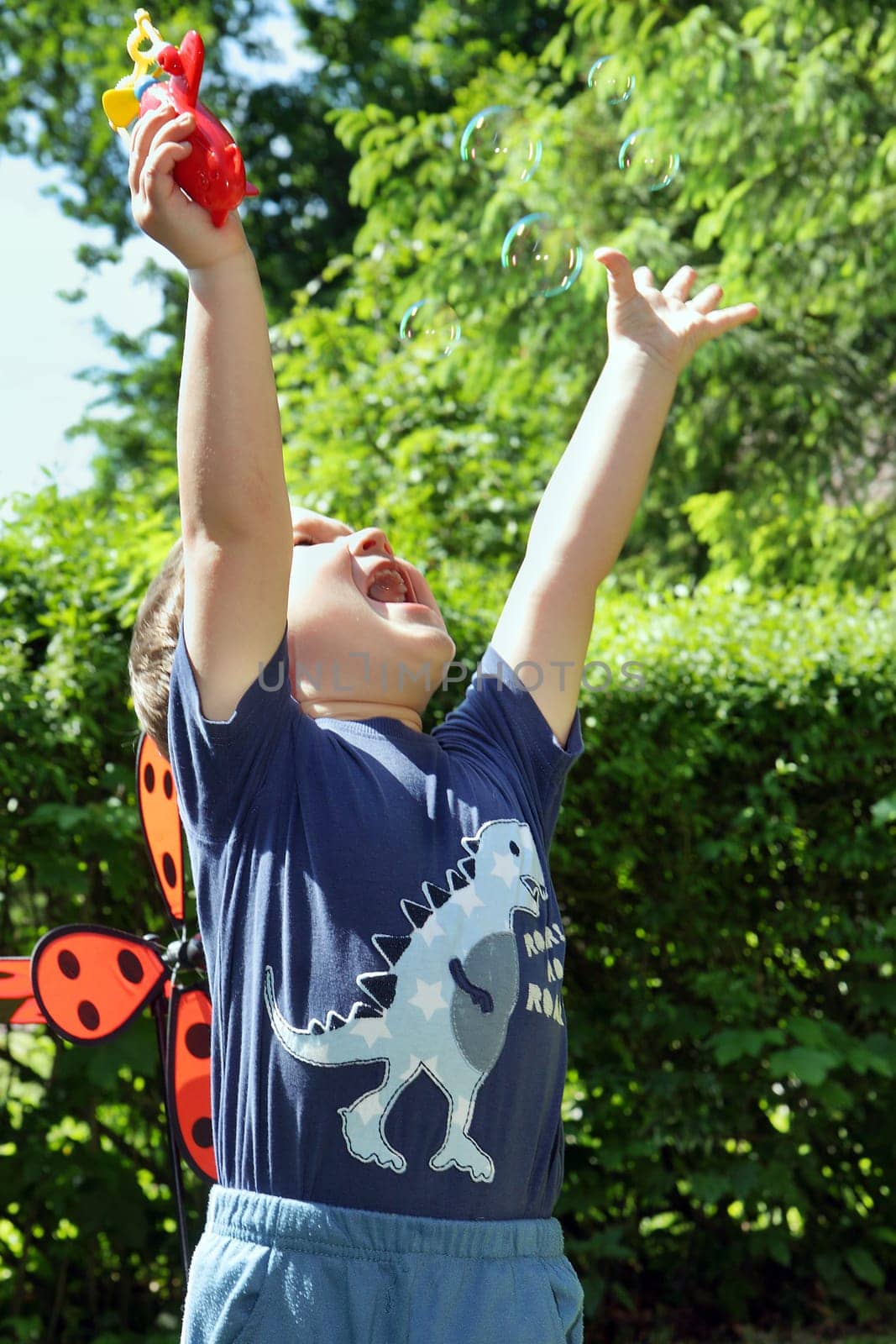 Little boy in the summer park blowing bubbles - trapping bubbles