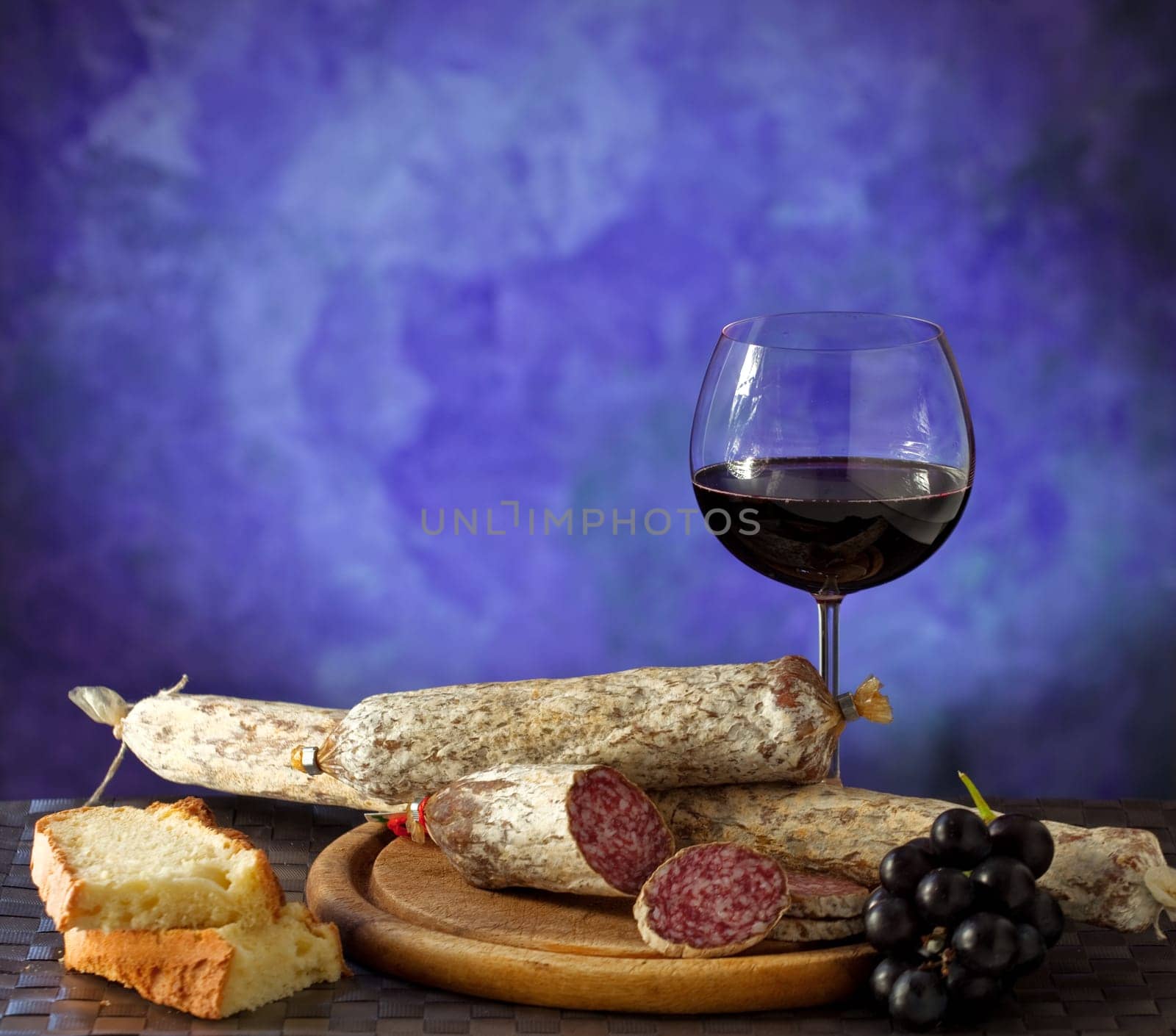 Salumi and glass of red wine on purple background
